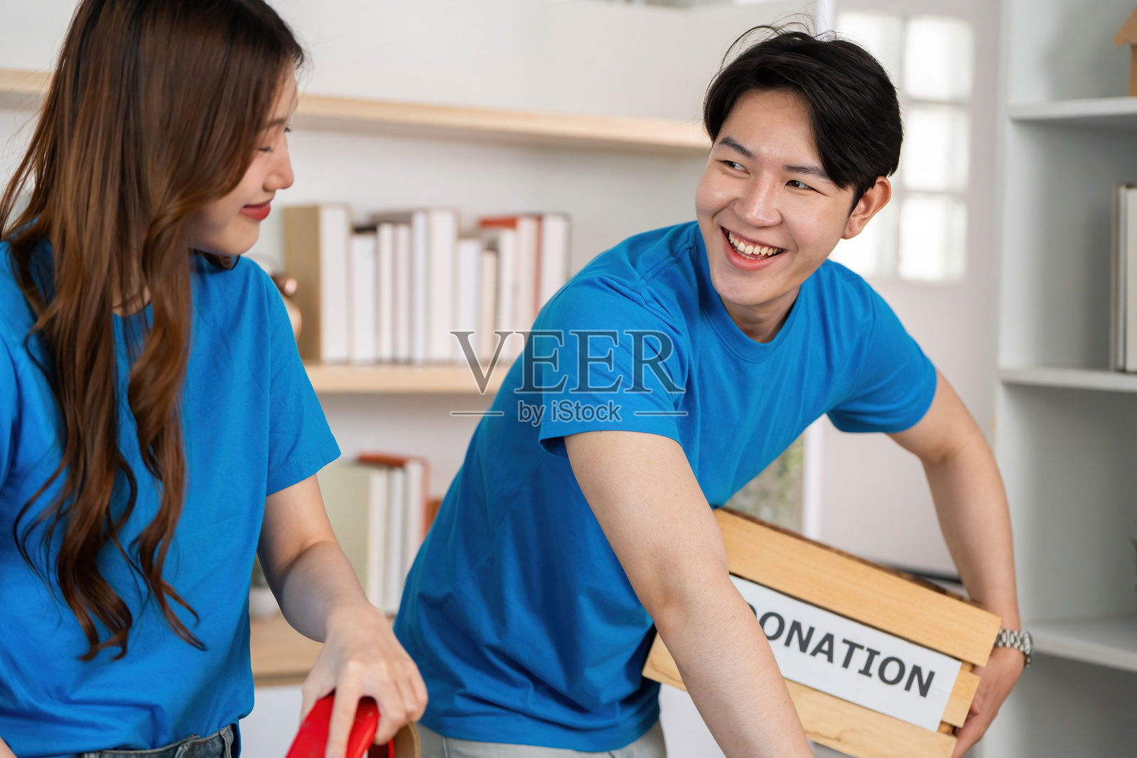 志愿者在社区中心微笑着递交捐赠箱。照片摄影图片