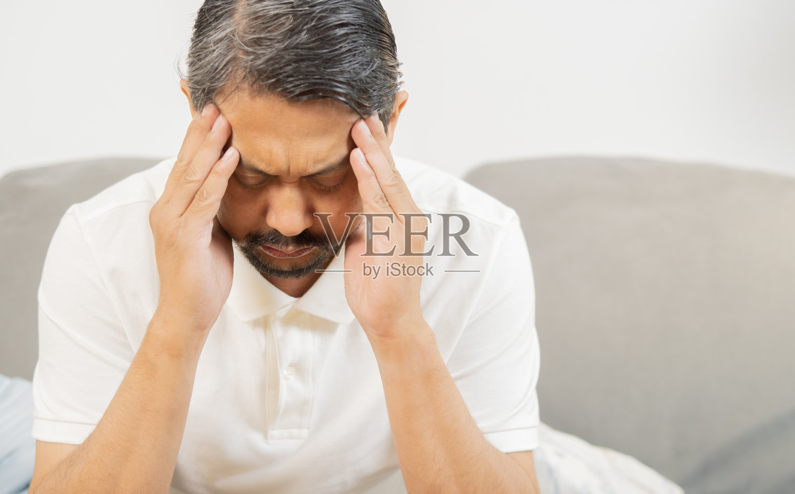 感到压力的成熟亚洲男性在家中遭受严重的头痛或偏头痛。照片摄影图片