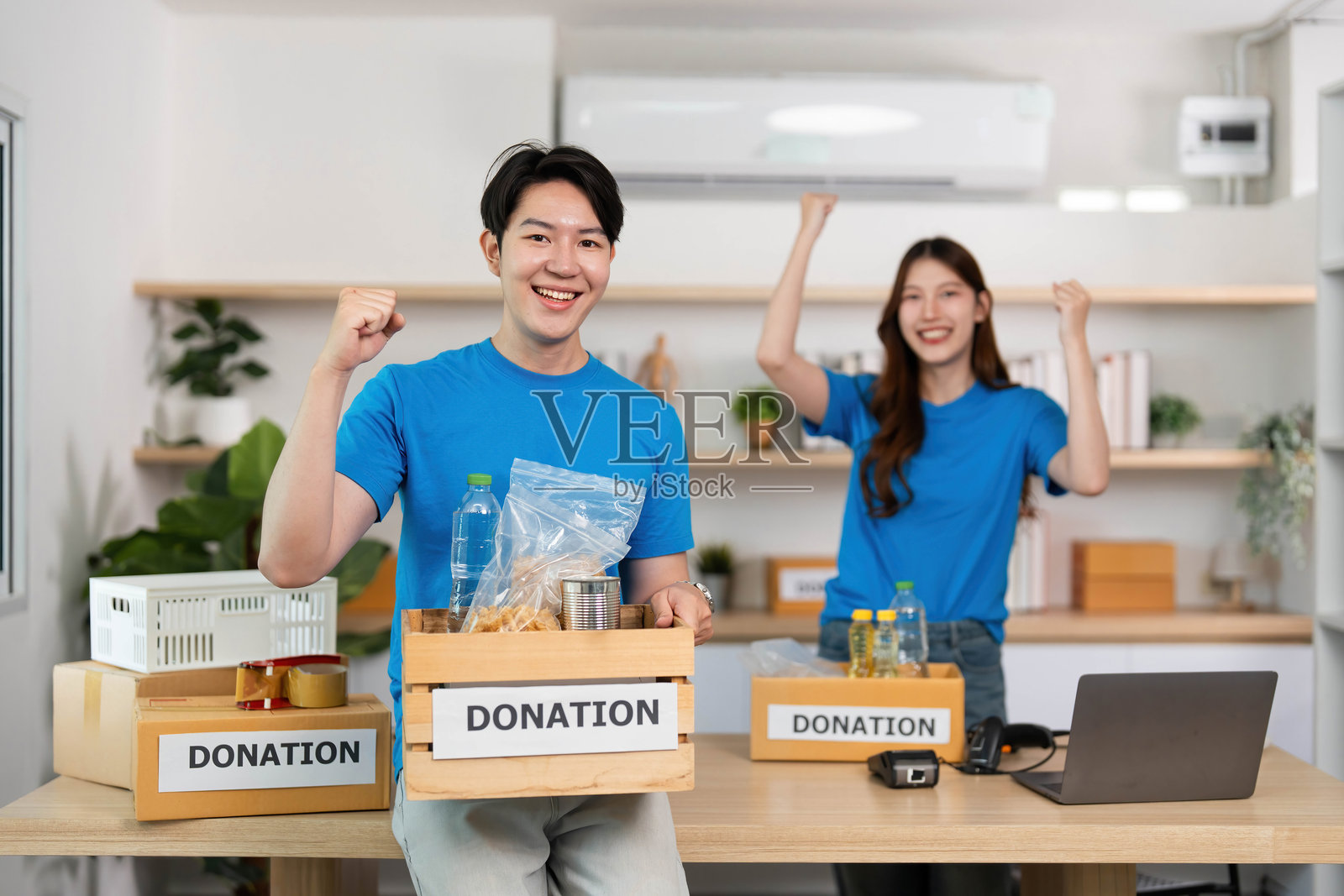 年轻志愿者在现代工作空间庆祝成功的食品募捐活动。照片摄影图片