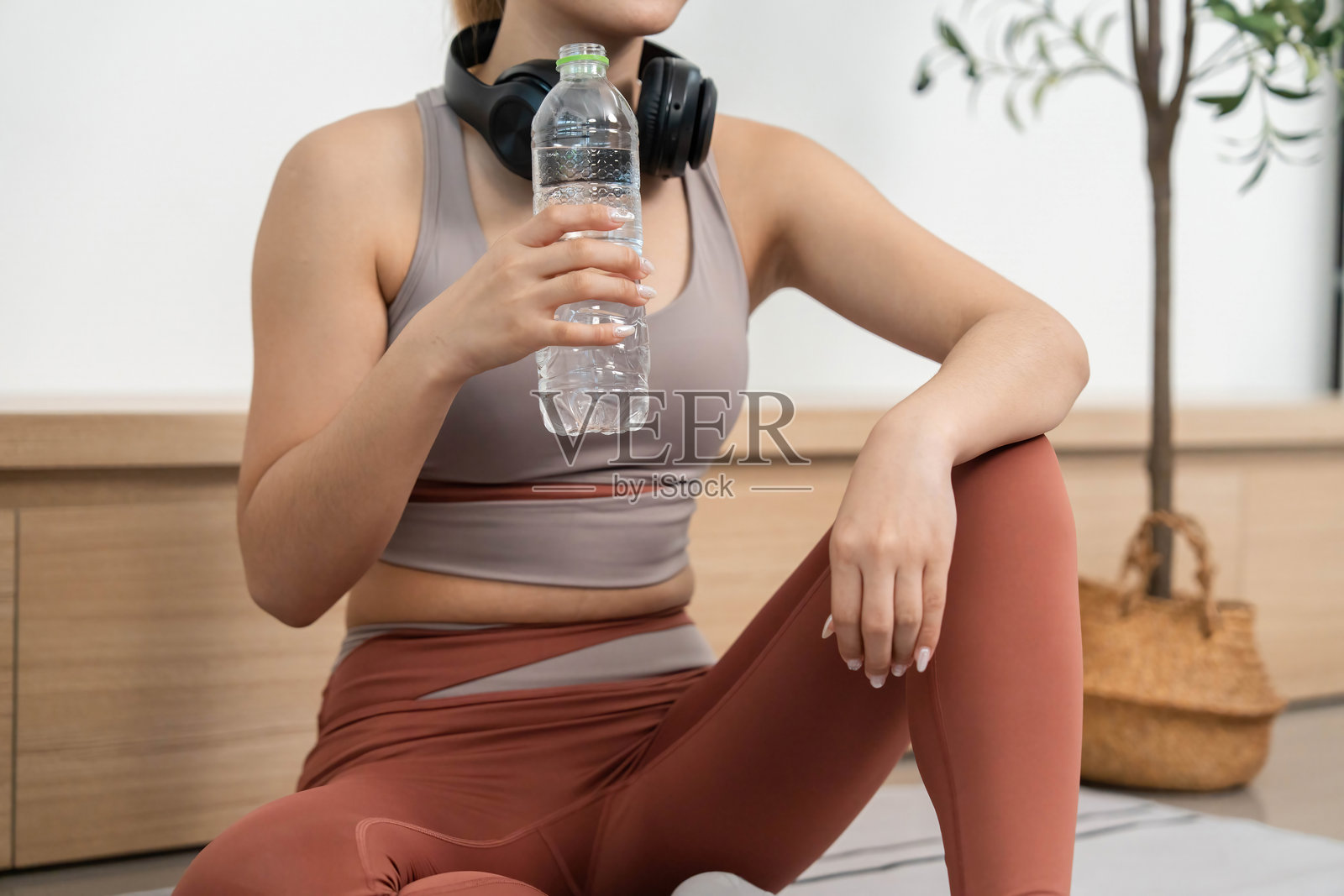 健身与健康。年轻女性享受休息时光，手里拿着水瓶和耳机。照片摄影图片