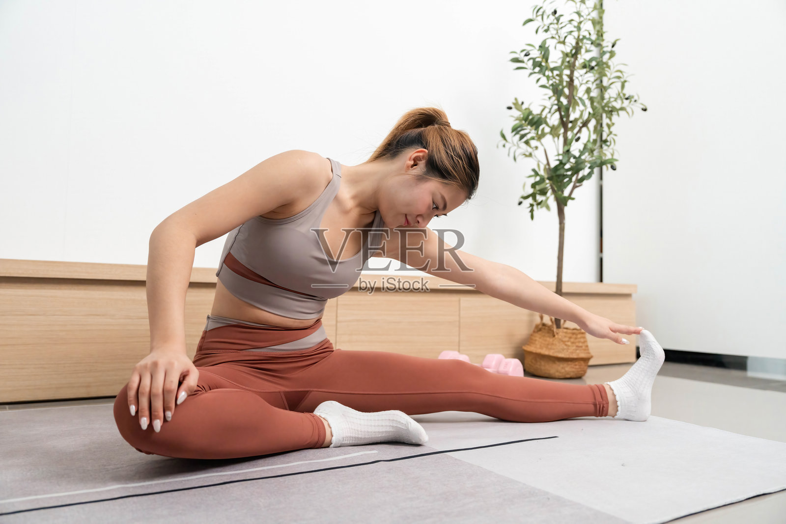 瑜伽与正念。女性在坐姿拉伸中伸手触脚，增强柔韧性。照片摄影图片