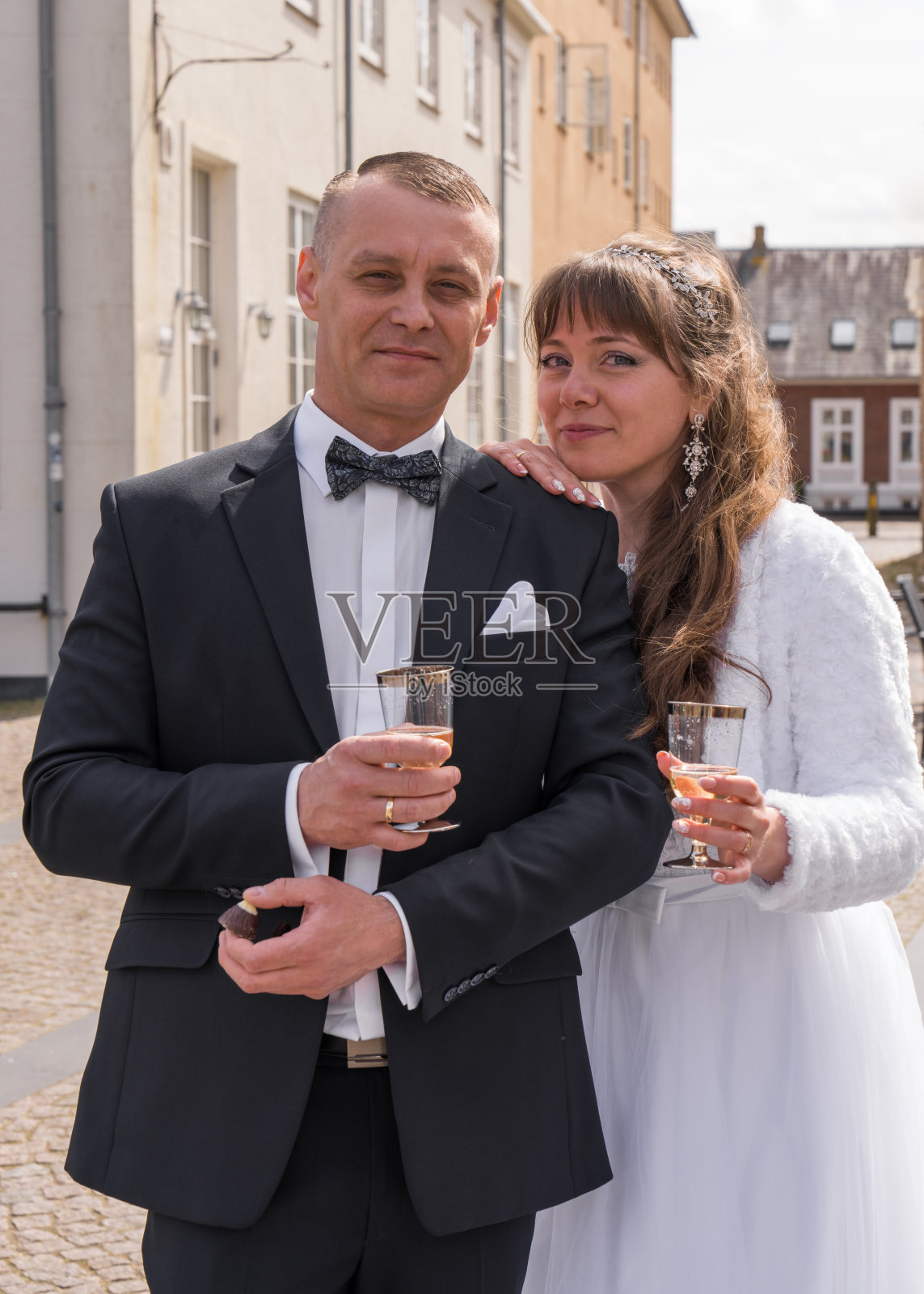 新婚夫妇在仪式后手持香槟杯庆祝这一时刻。婚礼庆祝。照片摄影图片