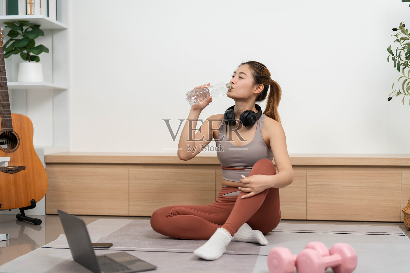 瑜伽与水分补充。女性在家练习瑜伽时喝水。照片摄影图片