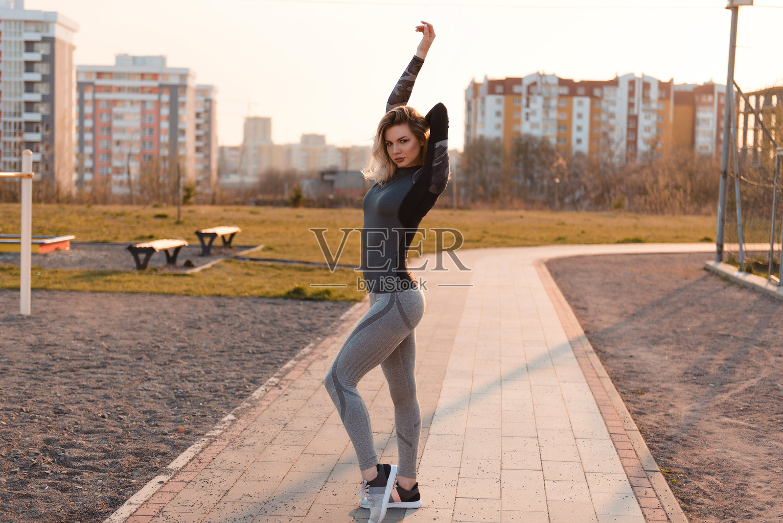 穿着紧身灰色运动服的性感女性对着镜头摆姿势照片摄影图片
