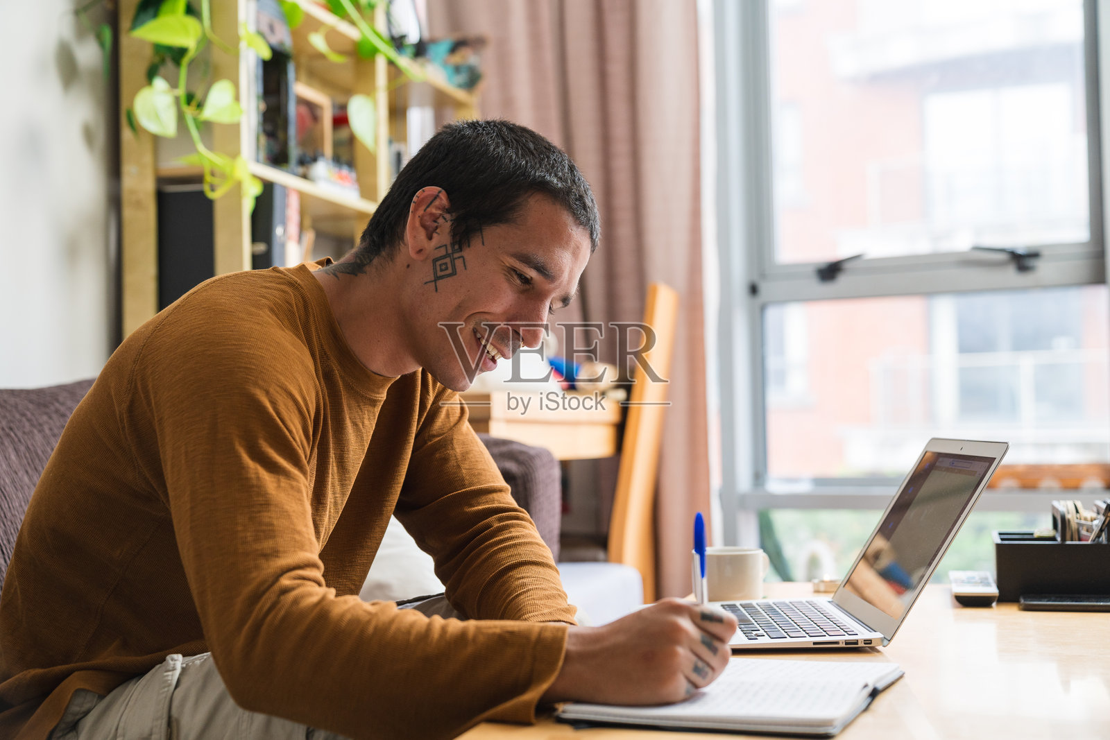 年轻的西班牙裔男子在家工作时做笔记照片摄影图片