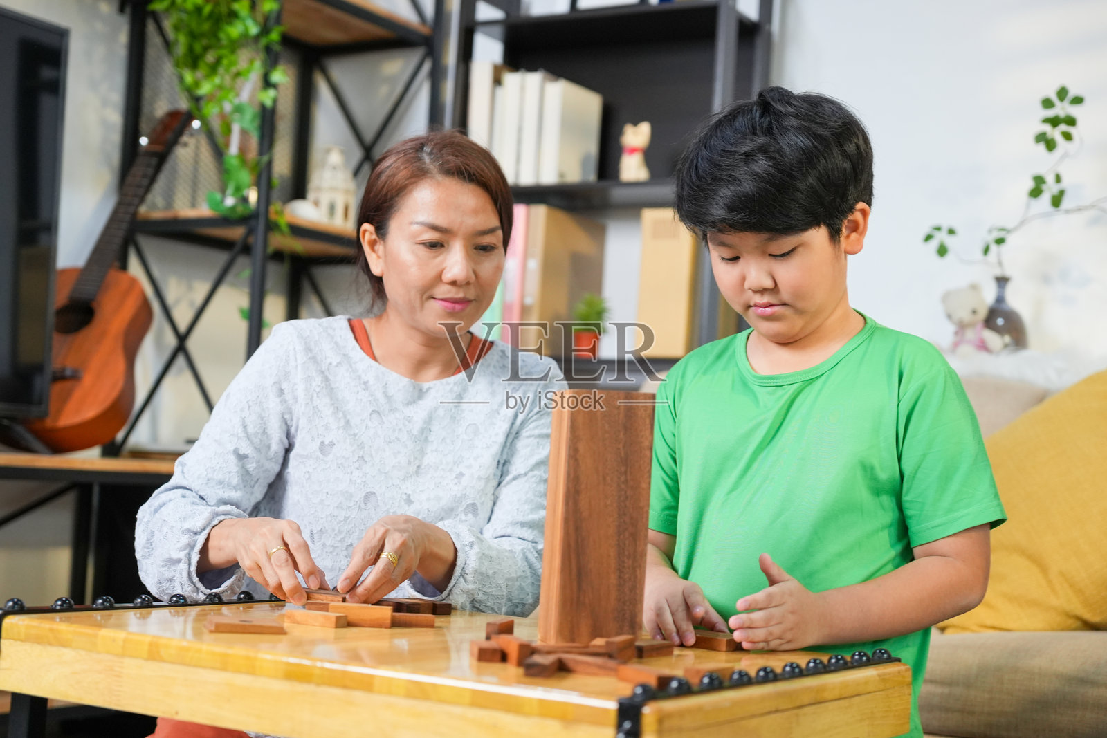 母亲和儿子在家客厅玩积木游戏，快乐的亚洲家庭享受有趣的室内游戏，父母与孩子一起度过美好时光。照片摄影图片