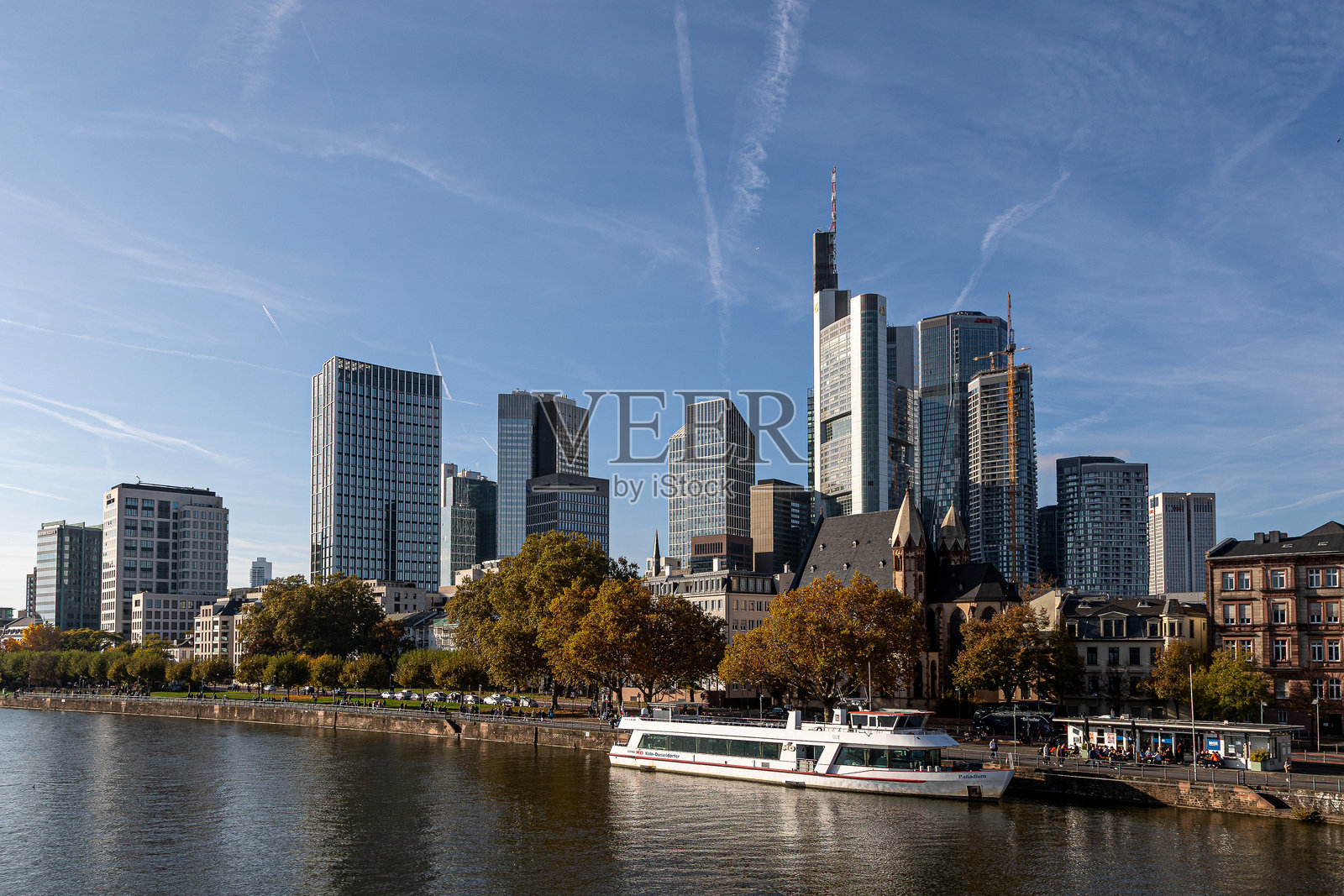 法兰克福天际线在美因河中倒影，五彩斑斓的秋季树木和停靠的游船。照片摄影图片