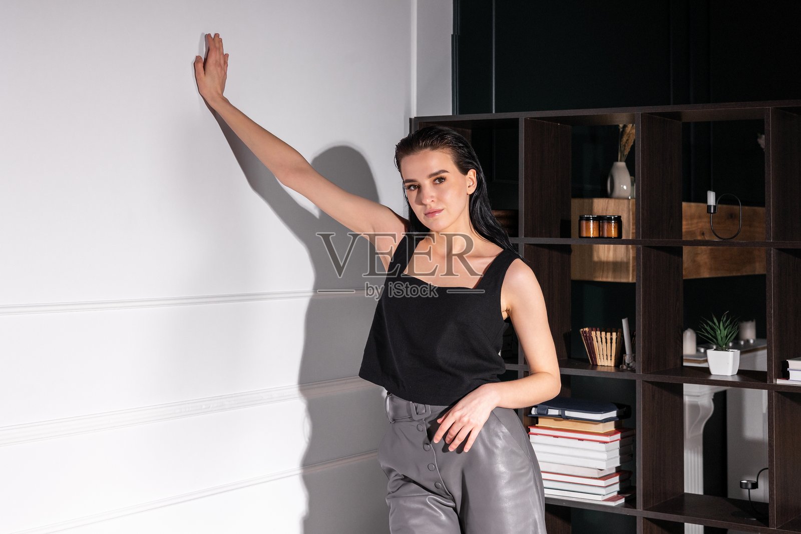 模特在干净的墙壁前自信地摆姿势，展示现代时尚和极简主义装饰。照片摄影图片