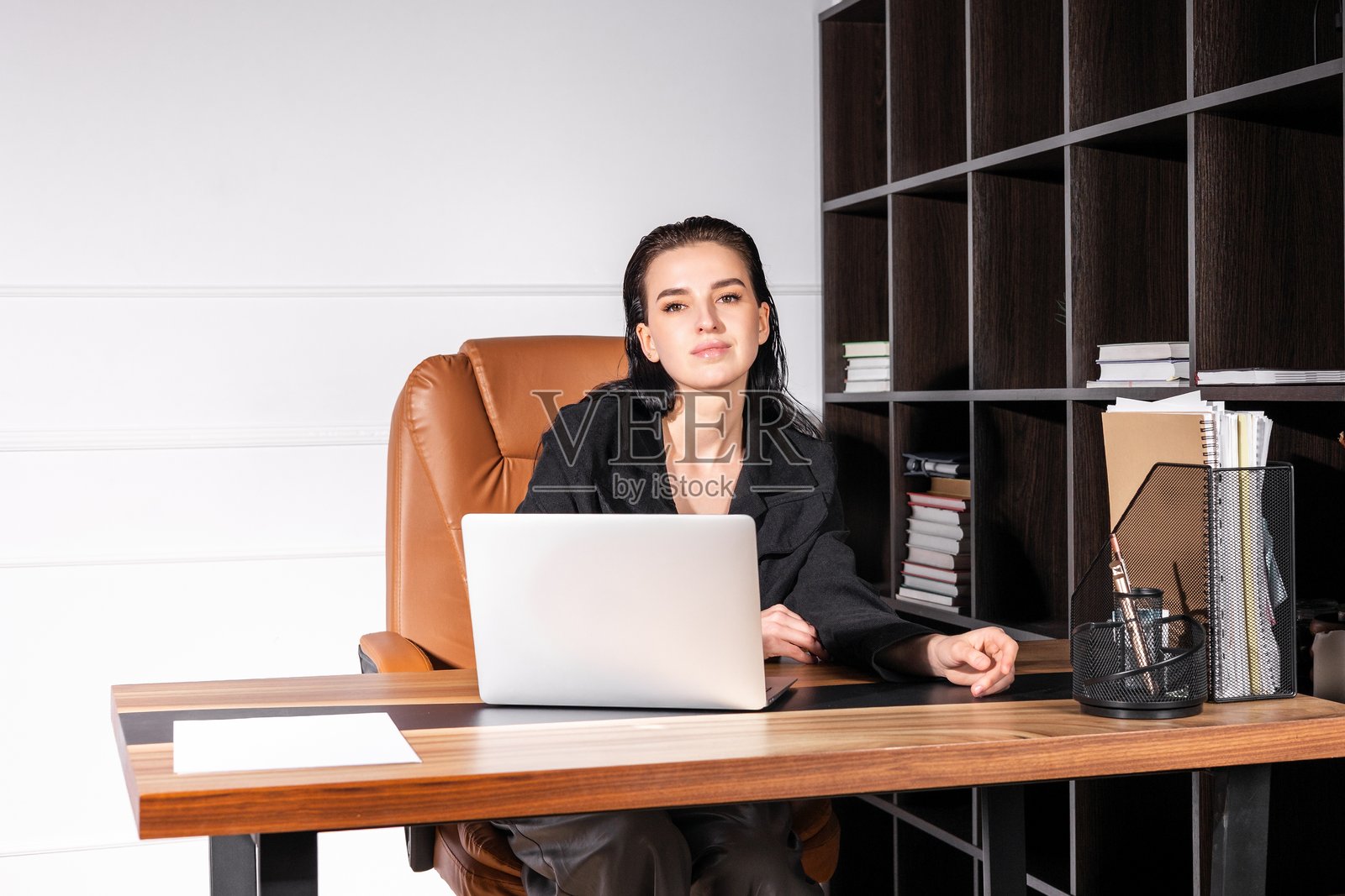 专业女性在时尚办公室的现代桌子上工作，桌上有笔记本电脑和整理用品照片摄影图片