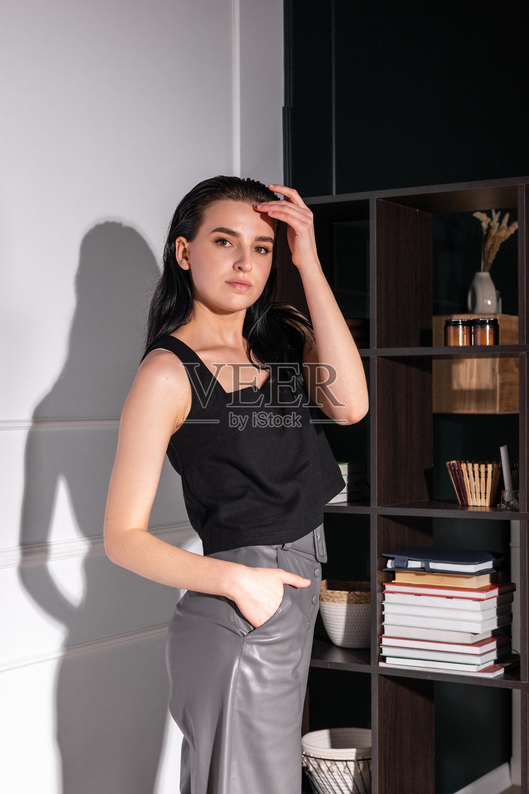 时尚年轻女性在现代时尚的阁楼环境中自信地摆姿势，自然光照亮了她的面容。照片摄影图片