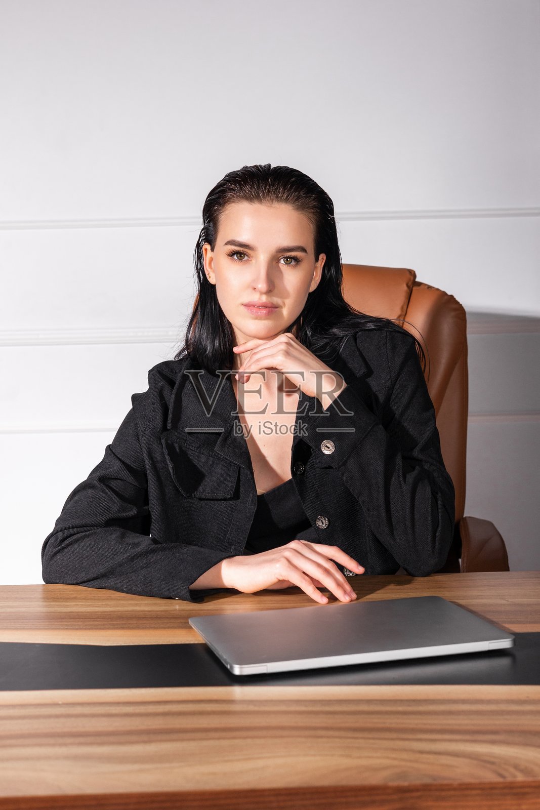 专业女性坐在现代办公室的桌子前，使用笔记本电脑准备会议，白天的环境。照片摄影图片