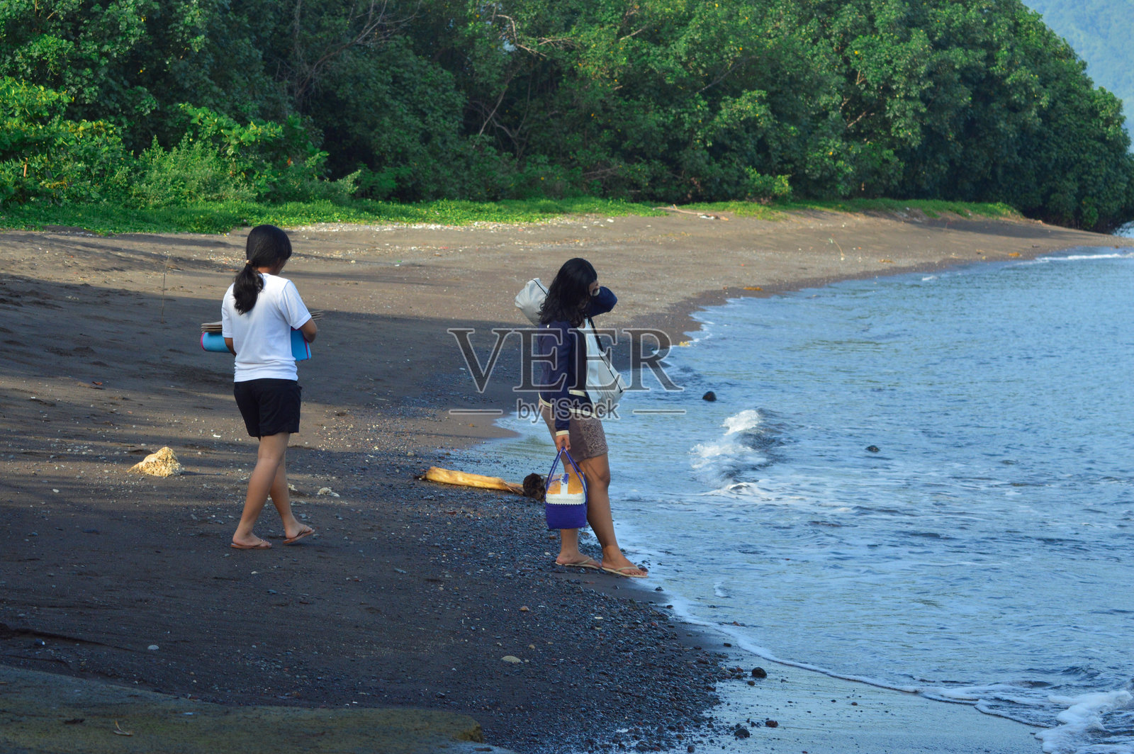 青少年女孩在沙滩上走，携带帐篷和用品照片摄影图片