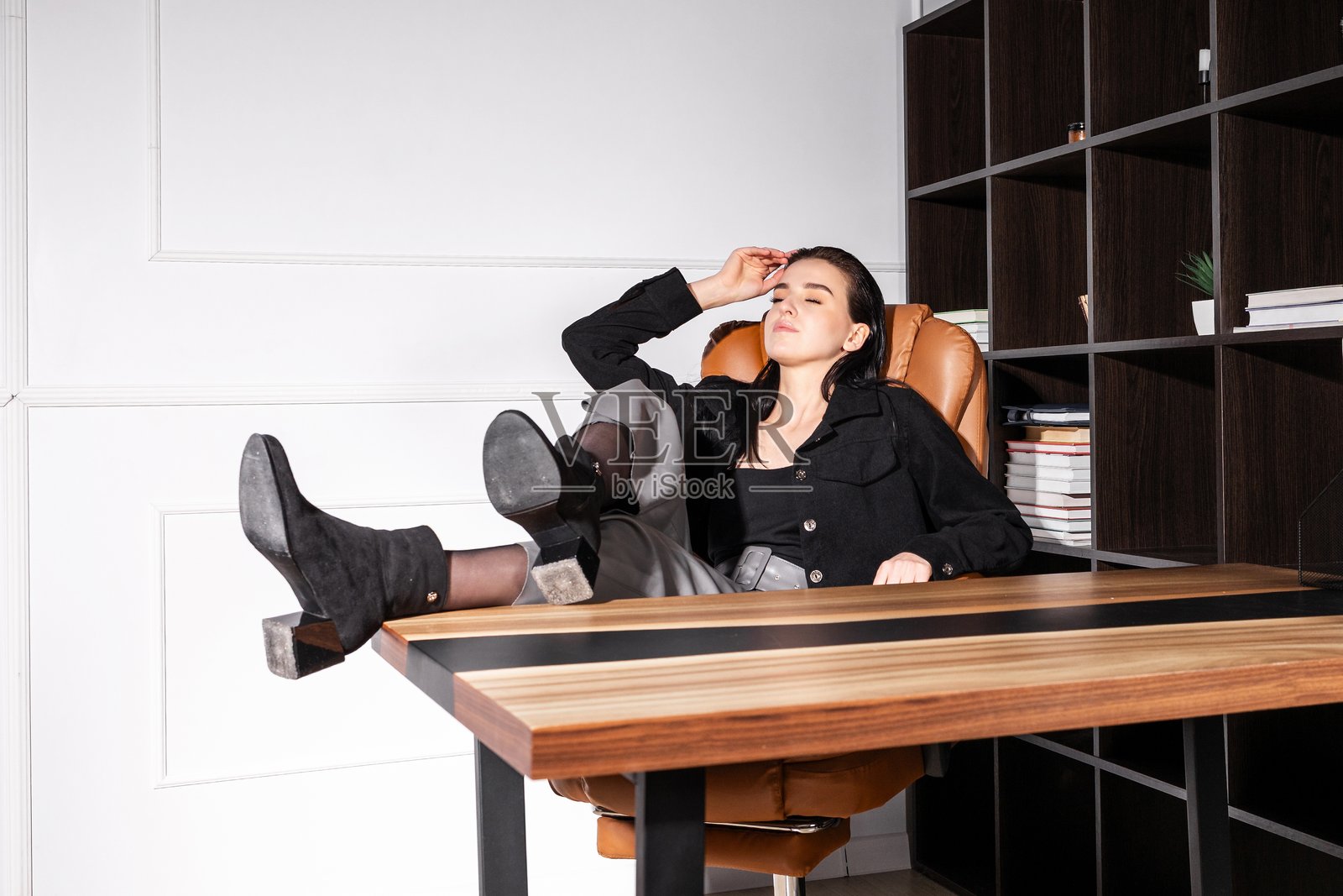 年轻女性在现代办公椅上放松，双脚搭在桌子上，正在家中进行项目工作照片摄影图片