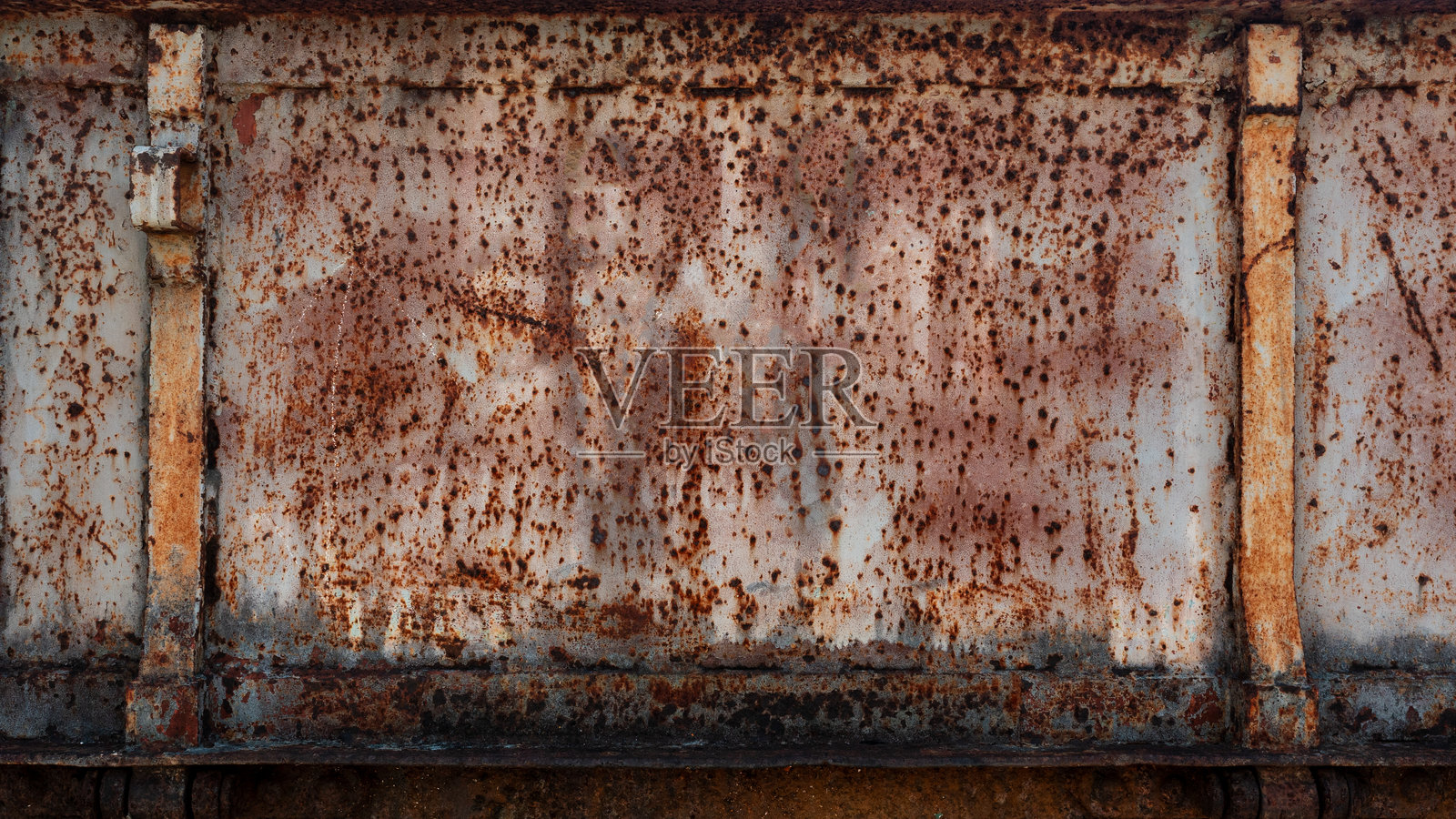 一个严重生锈和风化的金属表面，具有明显的面板和铰链，形成一种老旧的工业质感。照片摄影图片