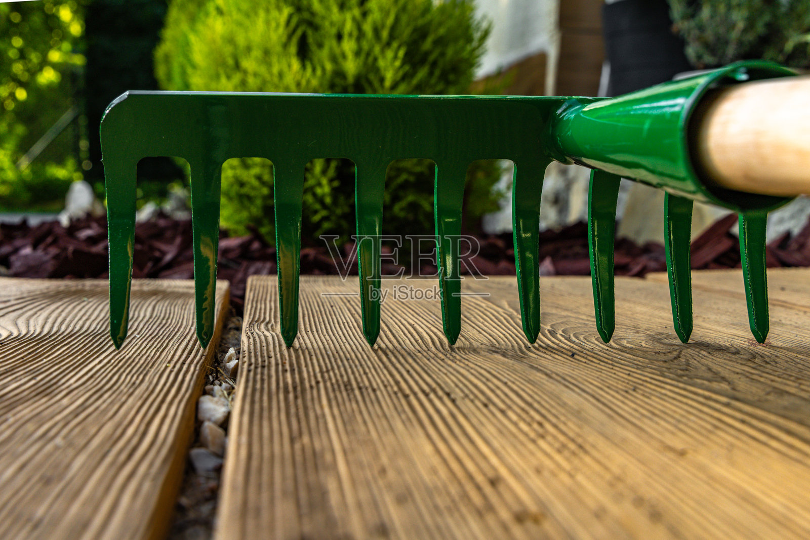 新绿耙子放在入口前的瓷砖上，用于耙叶子。照片摄影图片