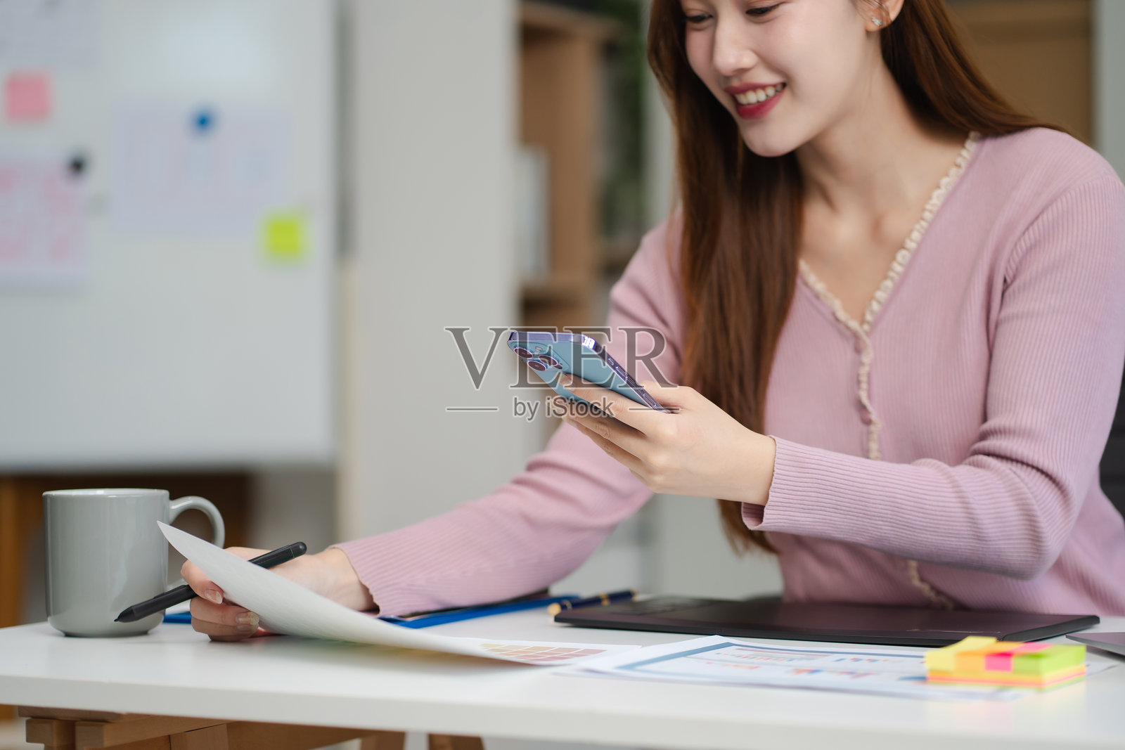 女性程序员或开发者在工作场所使用智能手机和电脑屏幕进行问题解决。照片摄影图片