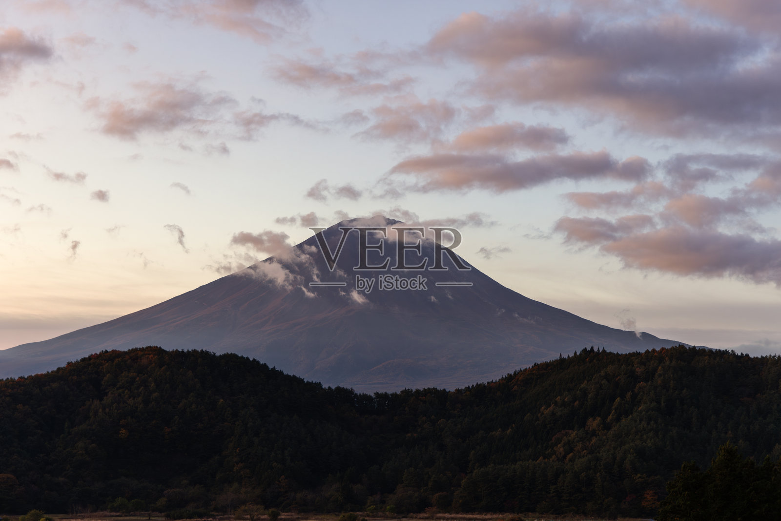 清晨的天空为富士山洒下柔和的光辉，散落的云朵环绕在山顶周围。照片摄影图片