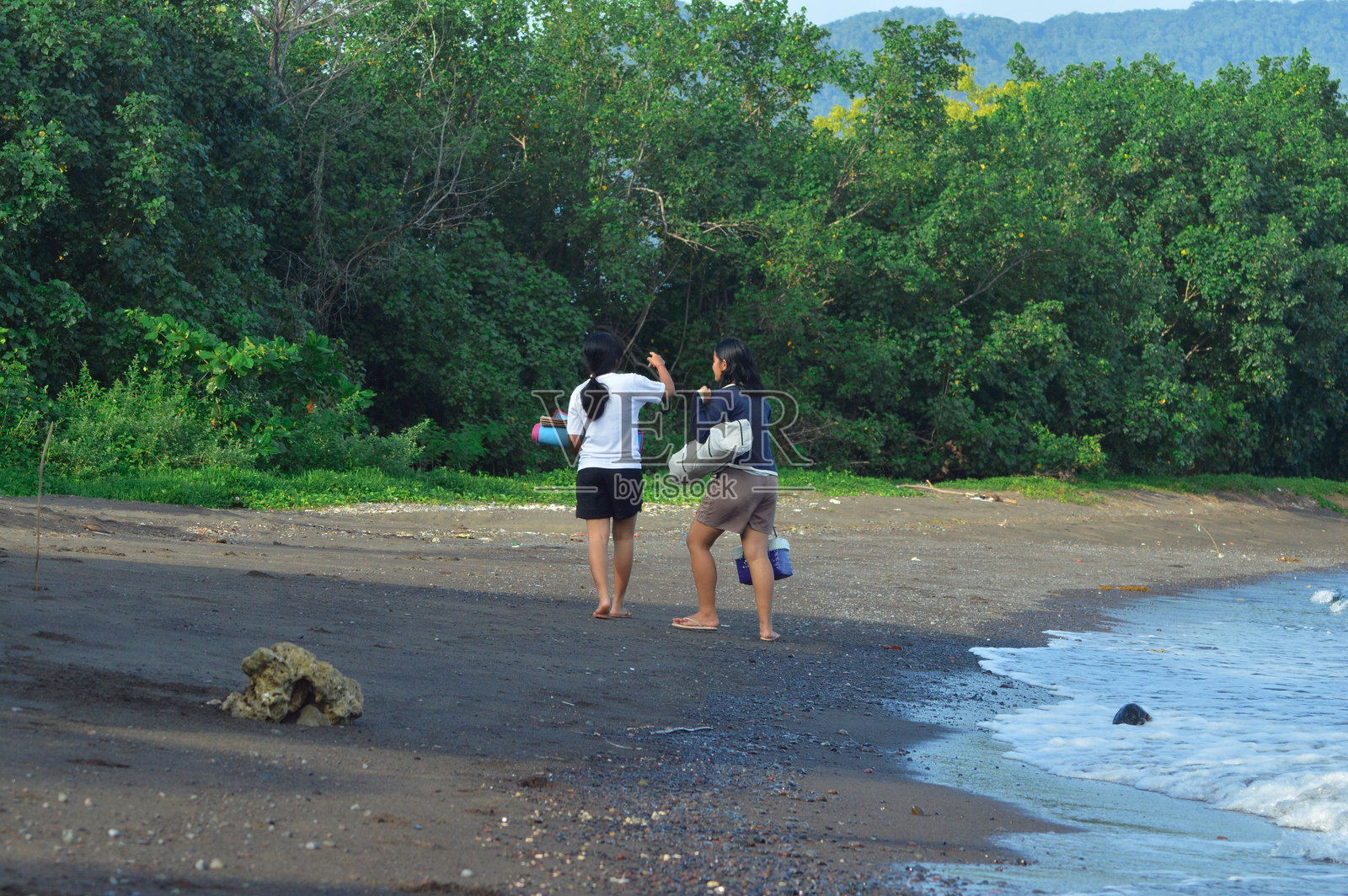 女孩们在海滩上漫步，寻找休息的地方照片摄影图片