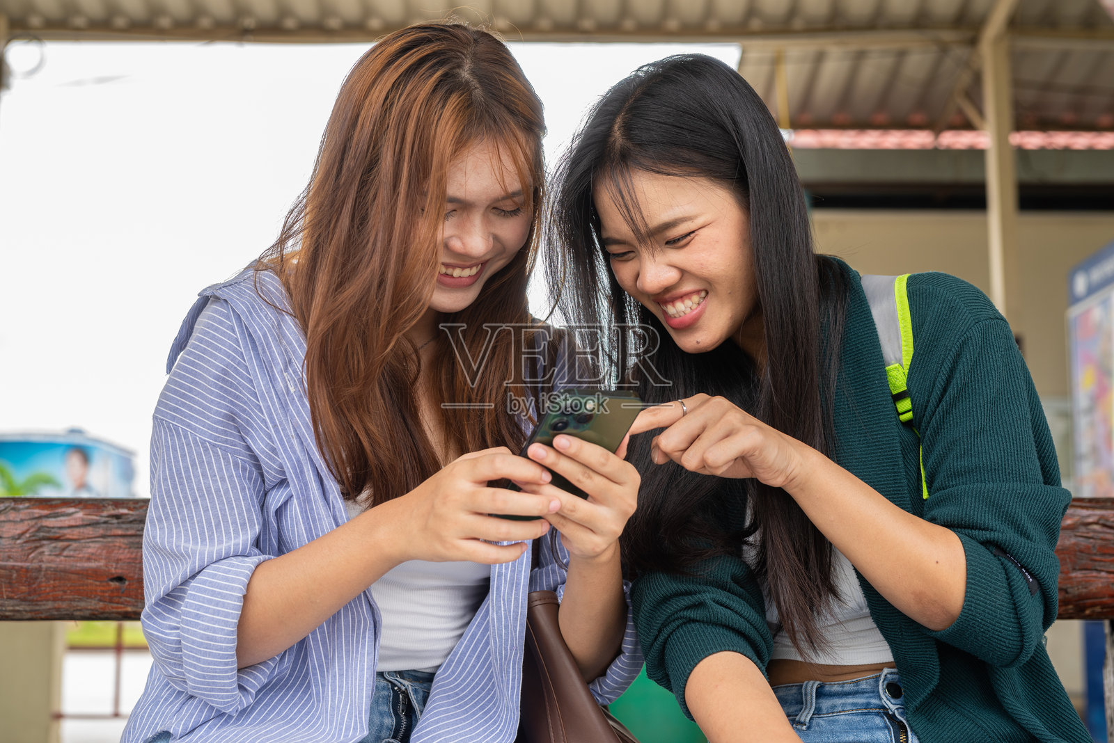 两位年轻女性在火车站一起。照片摄影图片
