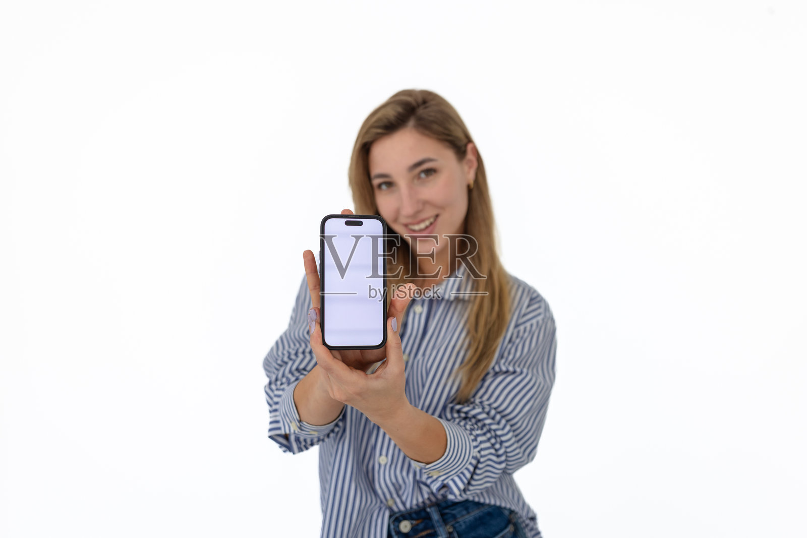 年轻女性在白色背景下与手机上的移动应用互动时微笑照片摄影图片