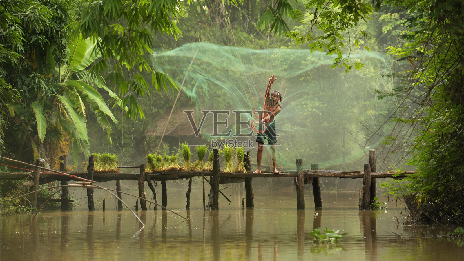 渔夫在桥上用鱼网在河里捕鱼照片摄影图片
