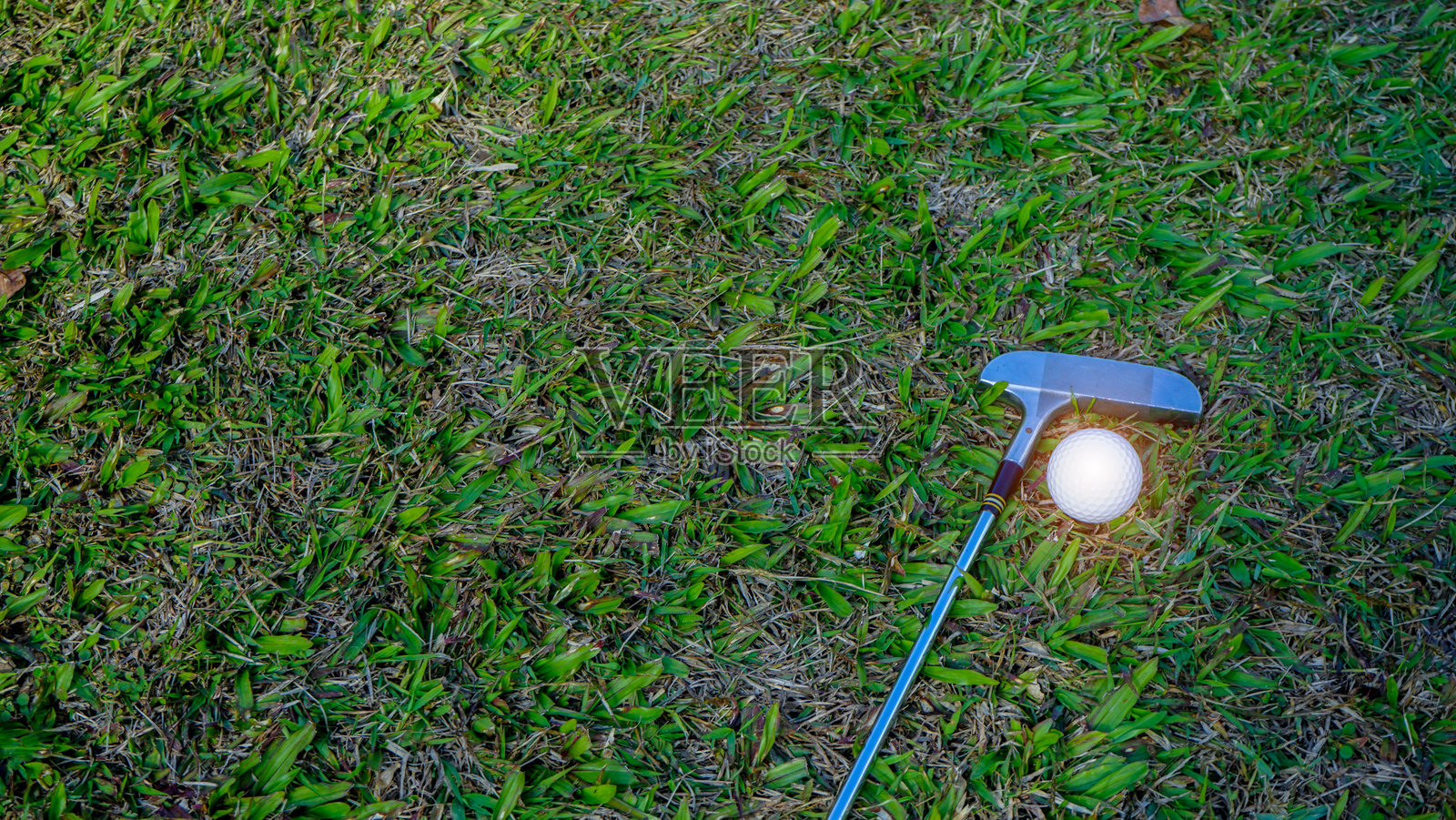 高尔夫球杆和高尔夫球在美丽的高尔夫球场绿草坪上，沐浴在晨光中。照片摄影图片