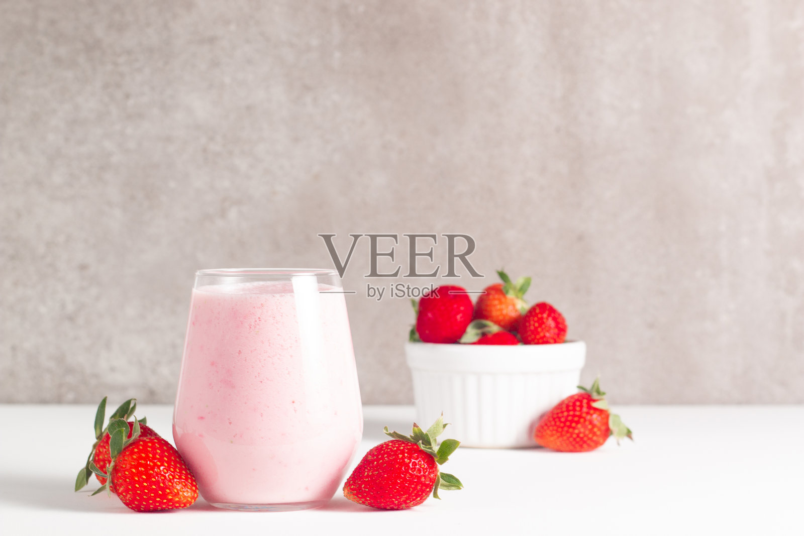 新鲜草莓奶昔、冰沙和新鲜草莓放在白色和木质背景上。健康食品和饮品概念。照片摄影图片