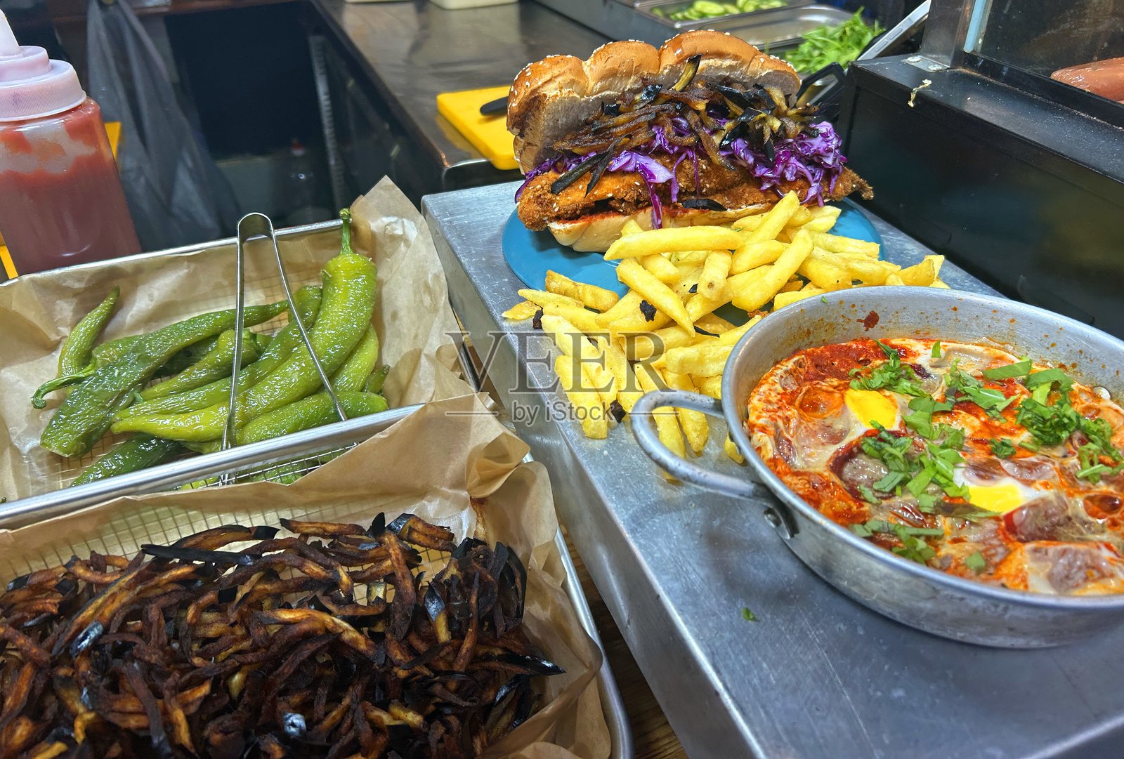 沙克舒卡是一道中东菜肴，由鸡蛋和番茄制成。辣椒、薯条，以及夹有炸肉排和茄子的哈拉面包。特拉维夫市场的街头美食。照片摄影图片