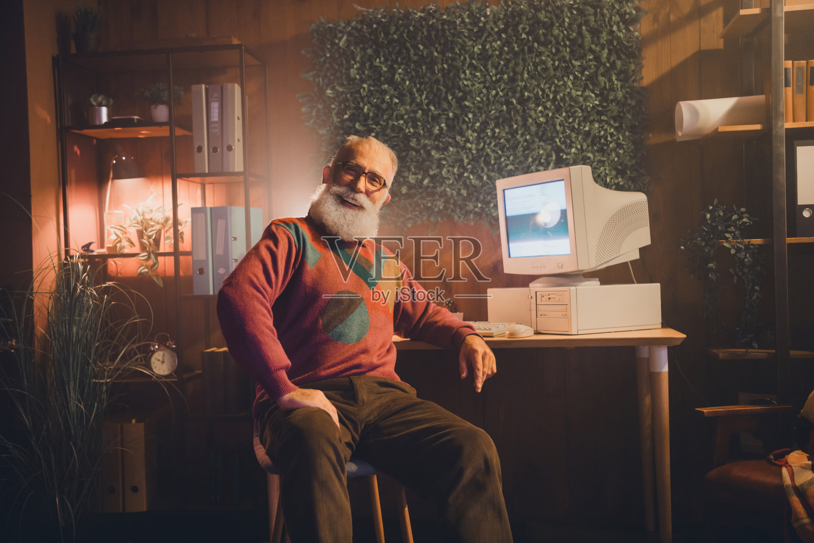 老年人在舒适的办公室里，配备复古科技设备，透过他放松而温暖的举止表达积极和怀旧的情感。照片摄影图片
