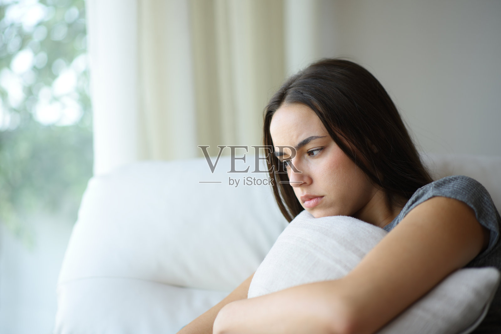 愤怒的女人在家抱着枕头照片摄影图片