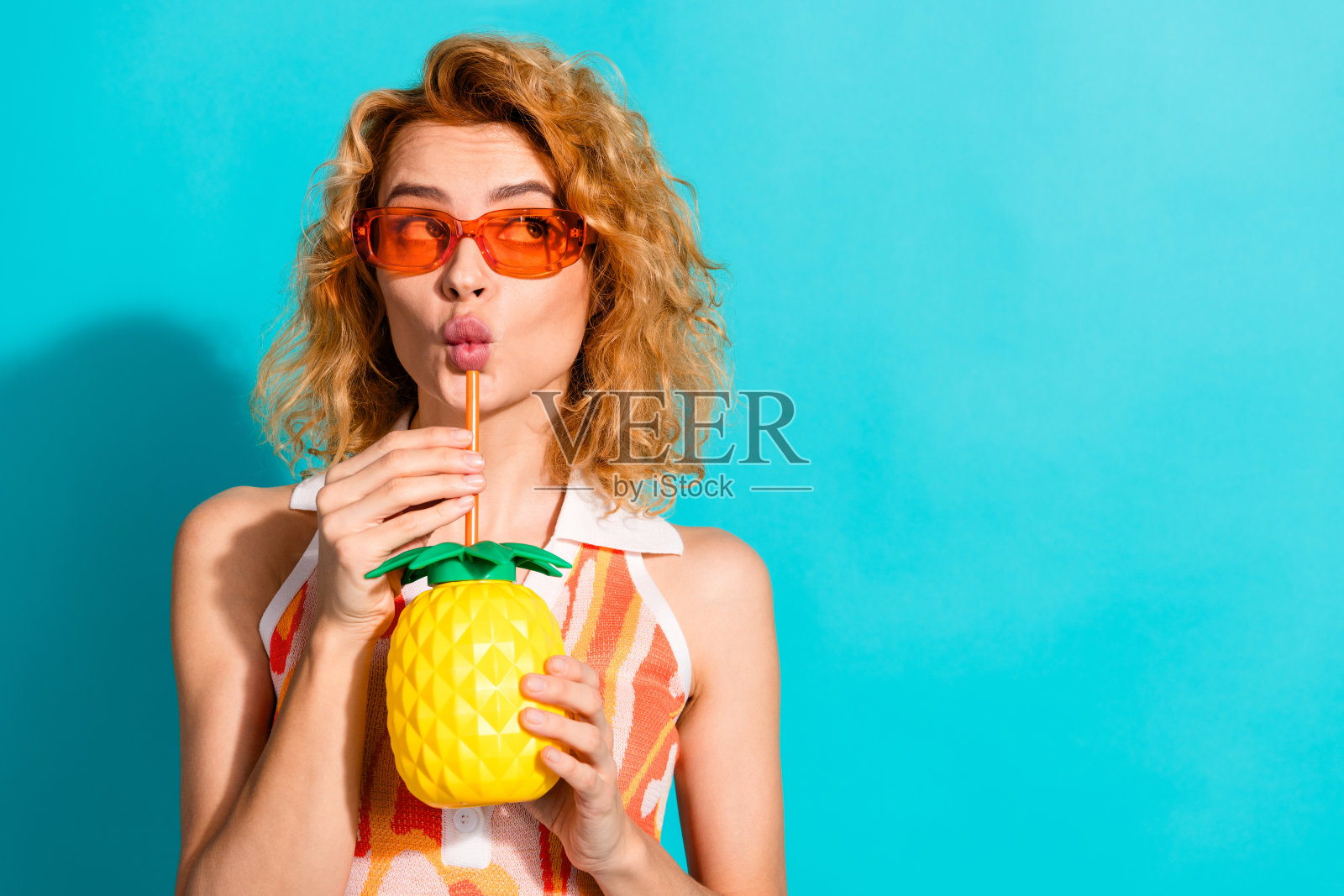 年轻时尚女性在充满活力的青绿色背景下享用清爽饮品照片摄影图片