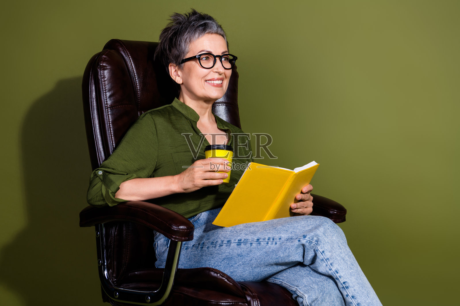 迷人的老年女性穿着休闲服，享受悠闲时光，阅读书籍并品茶，生活方式轻松自在。照片摄影图片