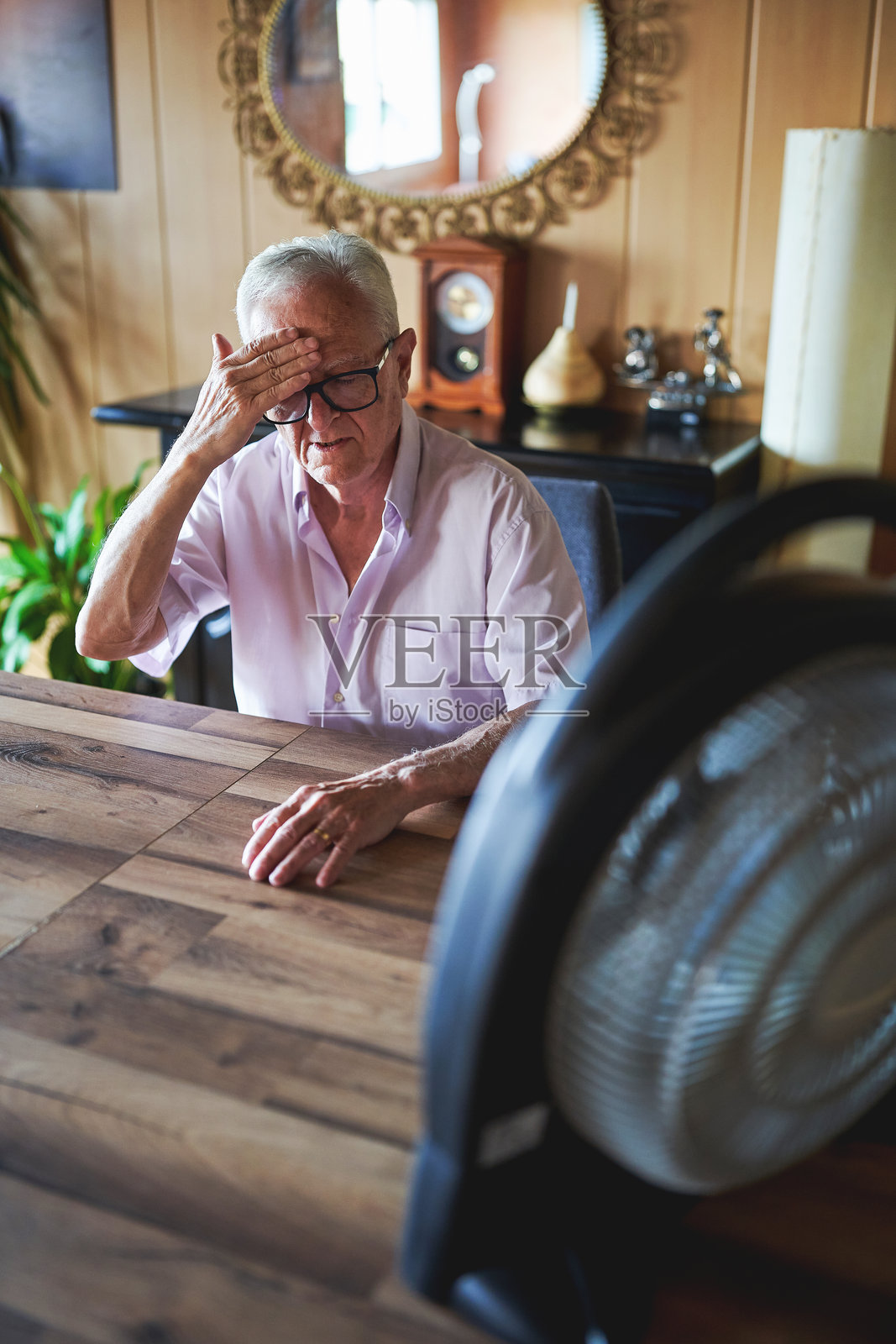 老年人在热浪中坐在家里感到炎热照片摄影图片