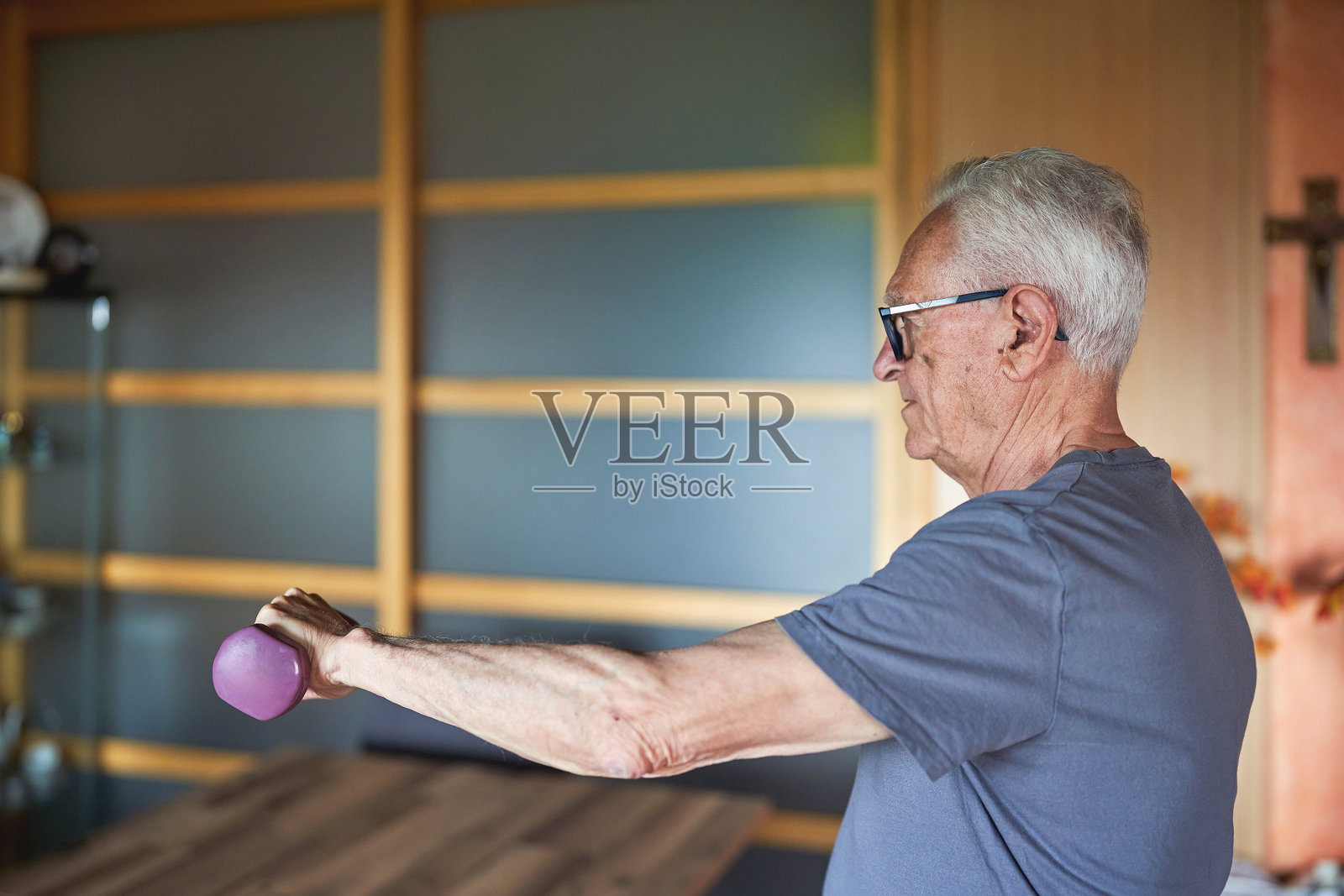 在家锻炼的老年男子，举着哑铃照片摄影图片