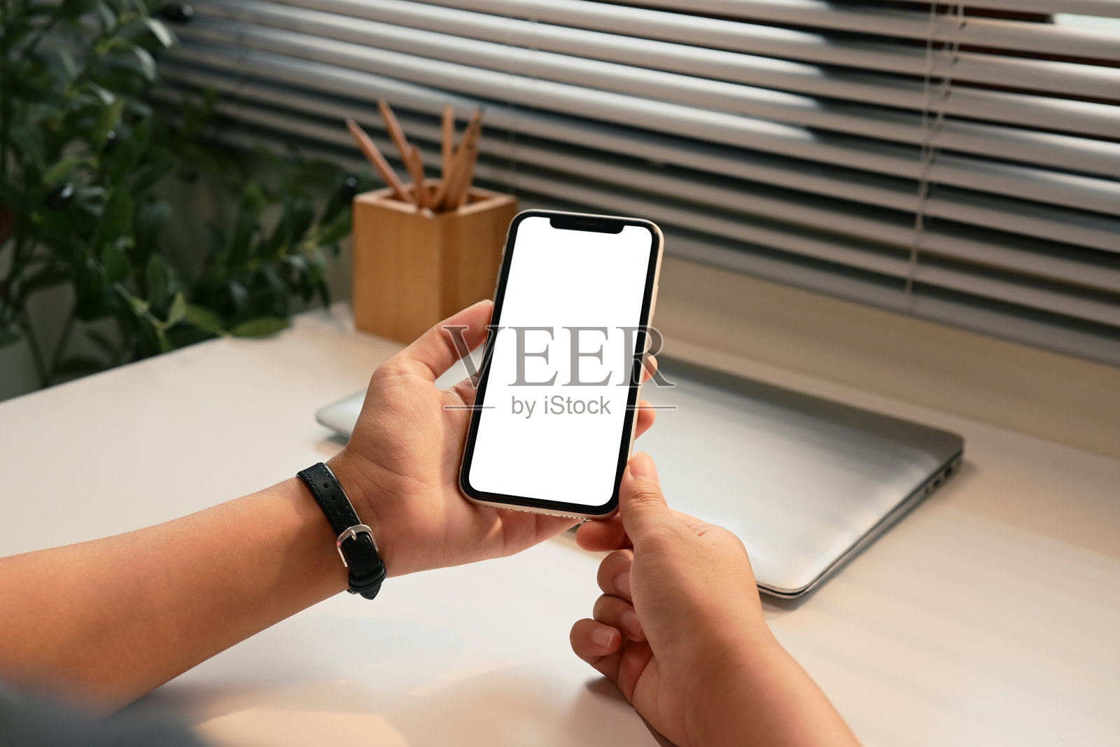 现代工作空间中，手握着一部屏幕空白的智能手机的特写镜头照片摄影图片