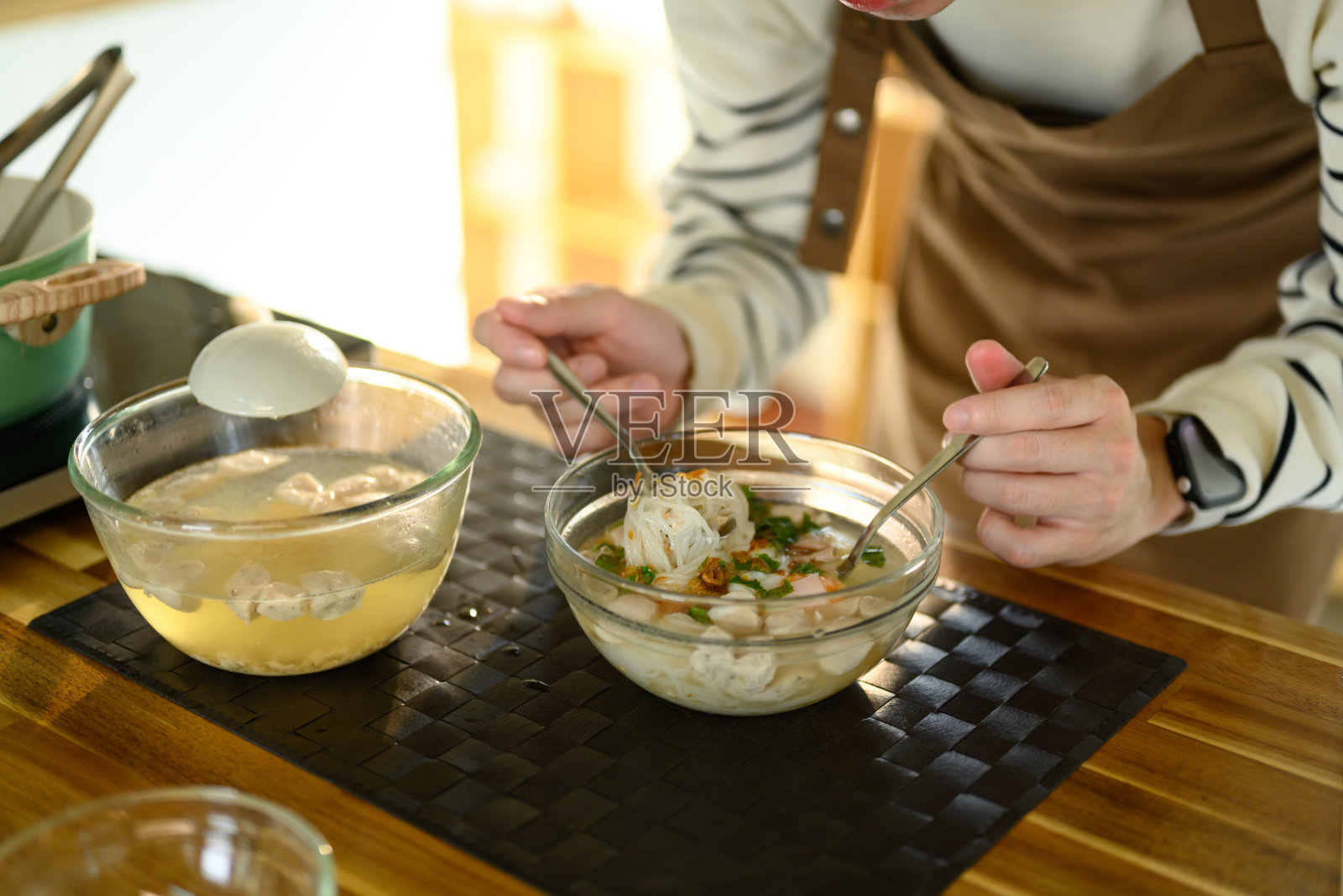 一个男人在温馨的厨房里准备一碗热腾腾的面条汤的特写镜头照片摄影图片