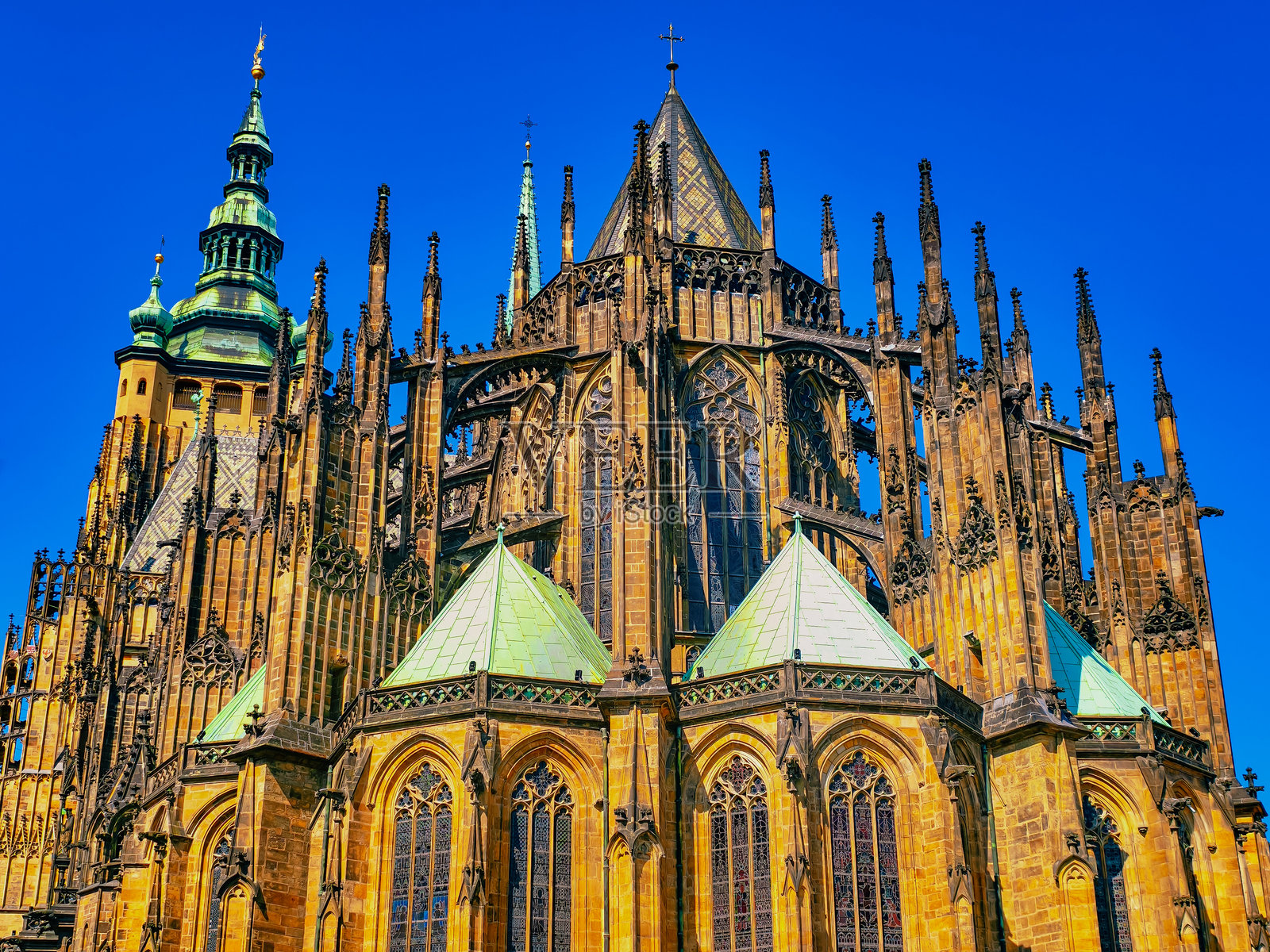 壮观的哥特式建筑景观，拥有复杂的尖顶和精致的石雕，背景是晴朗的蓝天。建筑独特的绿色屋顶和令人惊叹的彩色玻璃窗。照片摄影图片