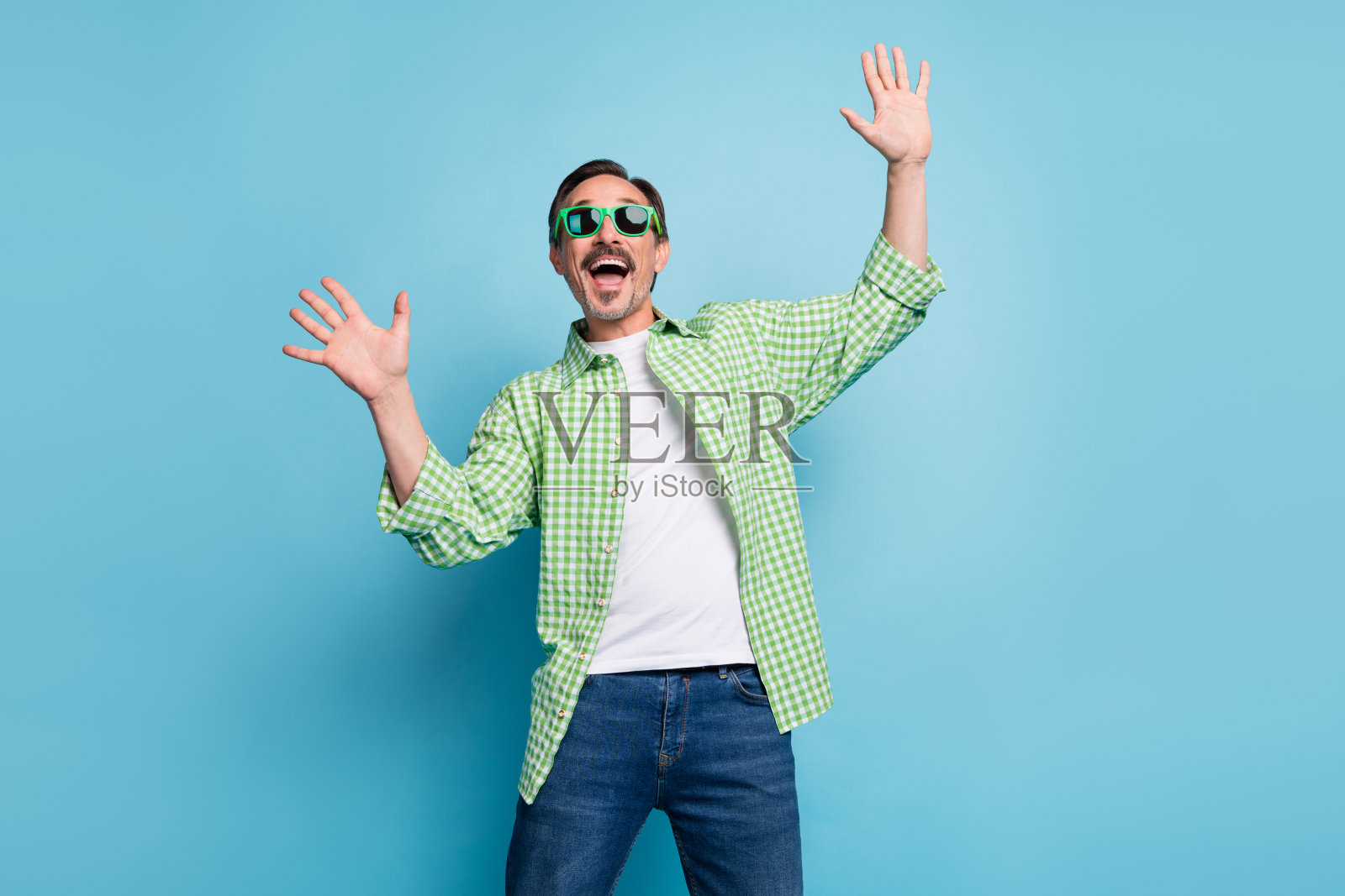 吸引人的快乐时尚男士在明亮的蓝色背景下跳舞、嬉戏，享受闲暇时光。照片摄影图片