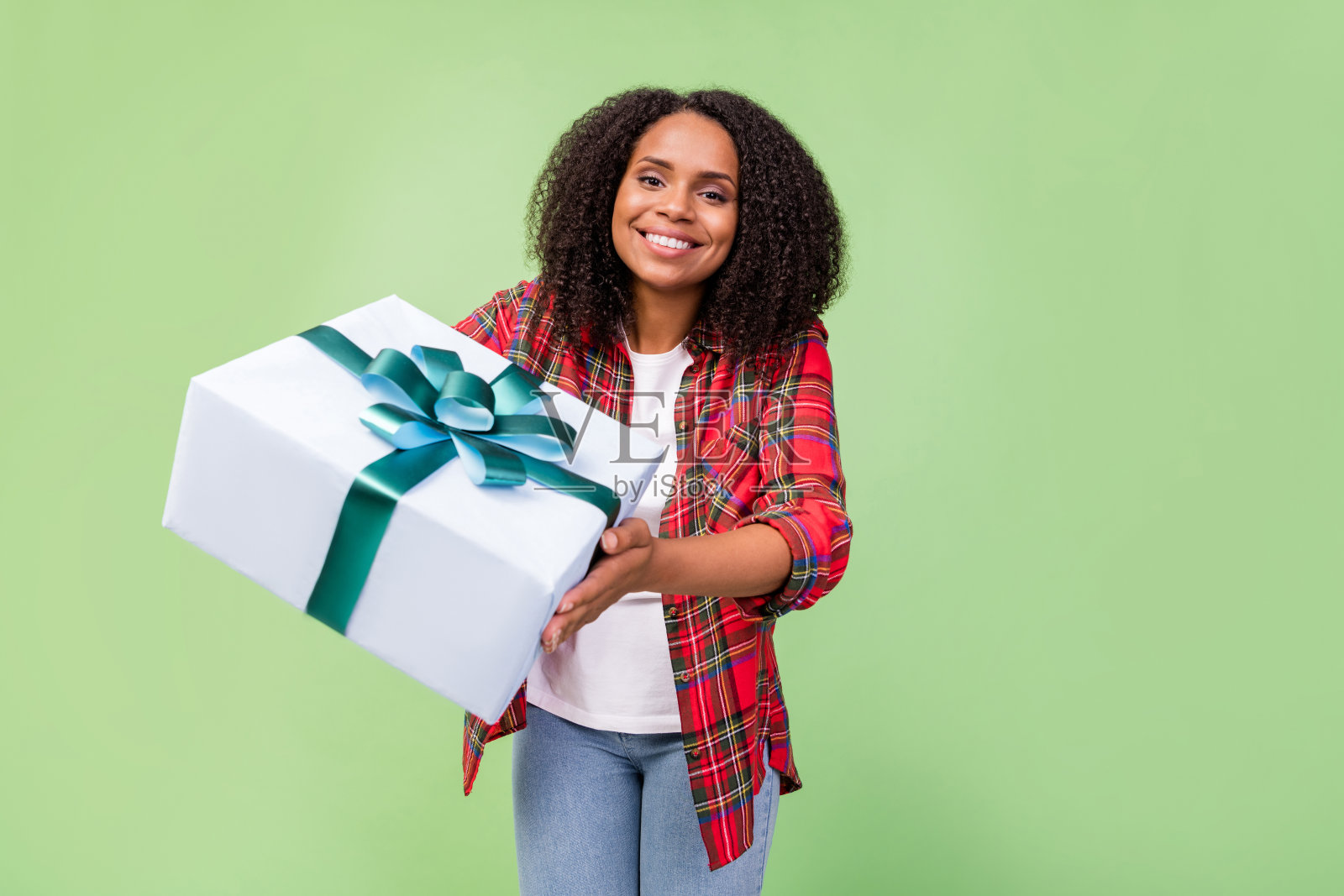 年轻迷人的非洲女性心情愉快，手持礼物盒，背景为绿色。照片摄影图片