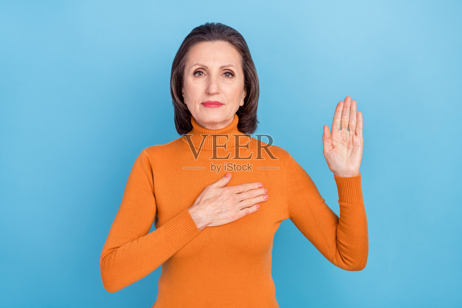 专注冷静的老年人手臂放在胸前，手掌抬起，背景为蓝色。照片摄影图片