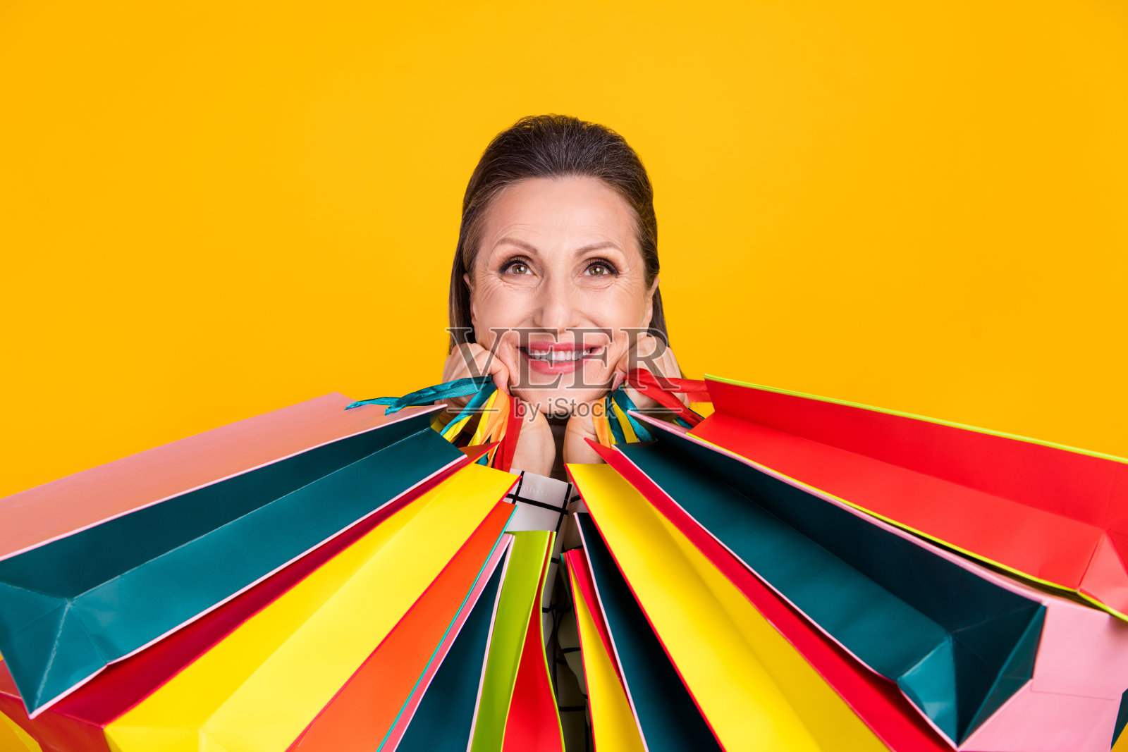 迷人而快乐的人露出灿烂的微笑，仰望空旷的空间，背景为黄色。照片摄影图片