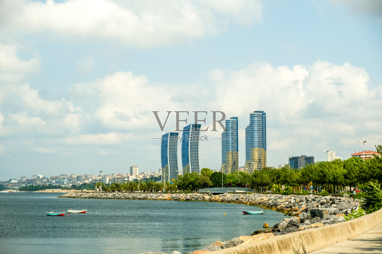 现代化的海滨长廊和公园，位于土耳其伊斯坦布尔，沿海岸线有步行道，天际线中高楼大厦在阳光明媚的日子里映衬着多云的天空。照片摄影图片