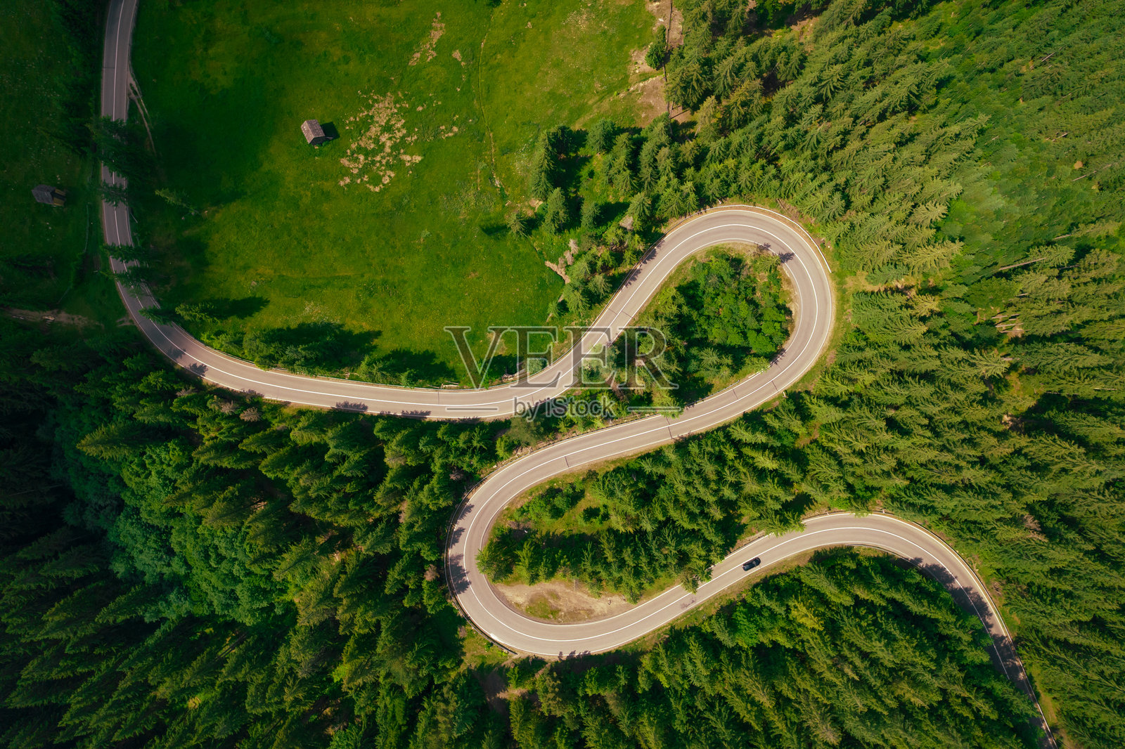 山间绿林中的公路鸟瞰图。夏季曲折的沥青公路穿过山林。照片摄影图片