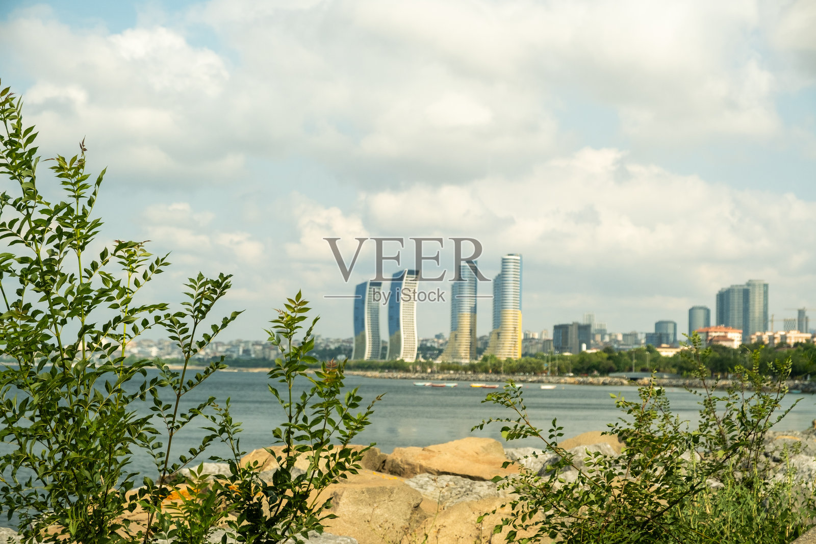 现代化的海滨长廊和公园，位于土耳其伊斯坦布尔，沿海岸线有步行道，天际线中高楼大厦在阳光明媚的日子里映衬着多云的天空。照片摄影图片