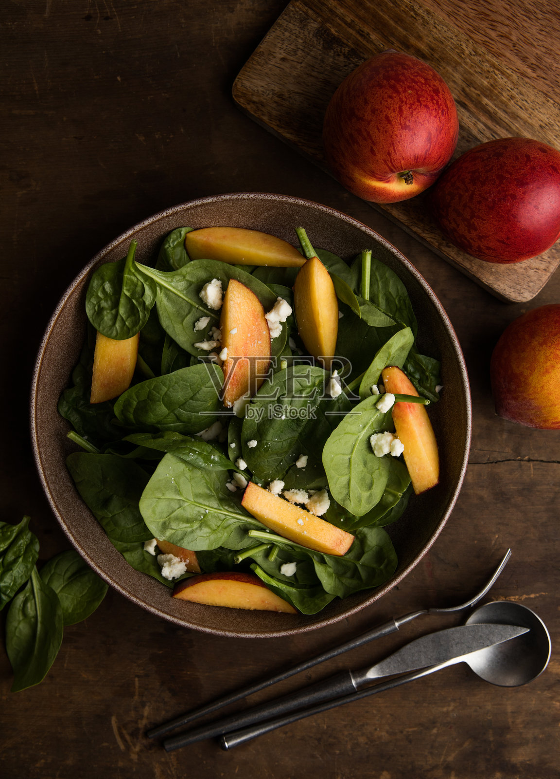 新鲜夏季沙拉，配有桃子、菠菜、微型绿叶菜和菲达奶酪，背景为木质纹理。健康饮食，清淡饮食，佛碗沙拉，俯视图。照片摄影图片