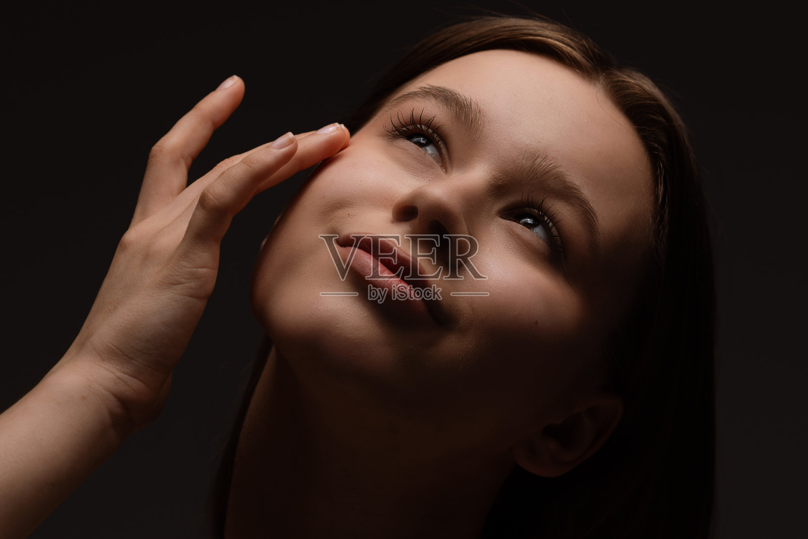 年轻女性在柔和的灯光下欣赏地触摸自己的脸庞照片摄影图片