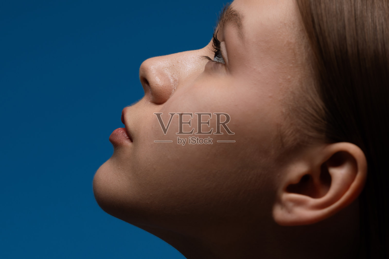 蓝色背景下面带宁静表情的女性侧面肖像照片摄影图片