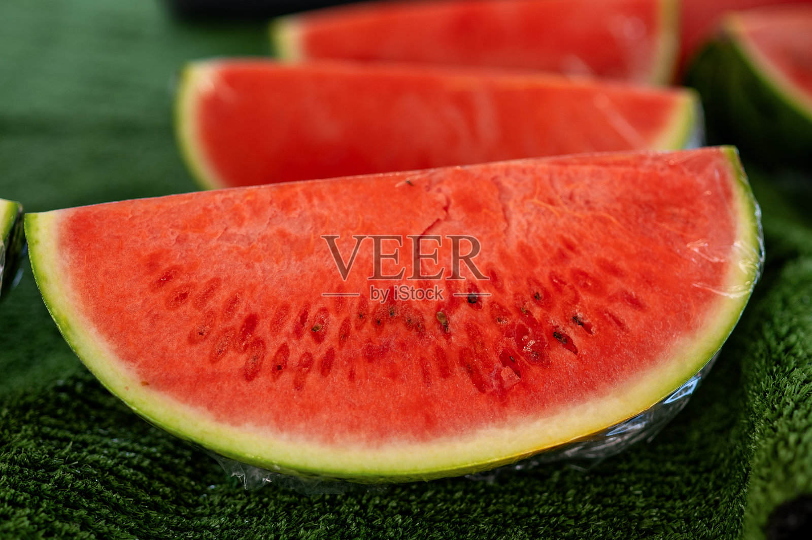 红色西瓜切片的特写，背景为绿色。照片摄影图片