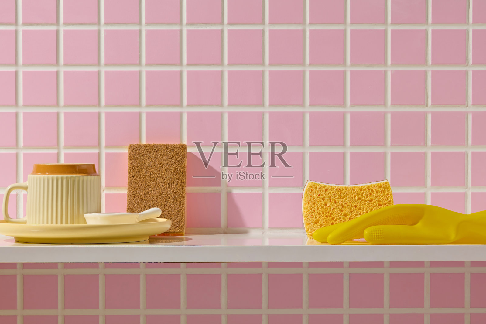 天然丝瓜络和棉质清洁布与黄色海绵一起摆放在白色台面上，背景是粉色墙砖，营造出环保的氛围。照片摄影图片