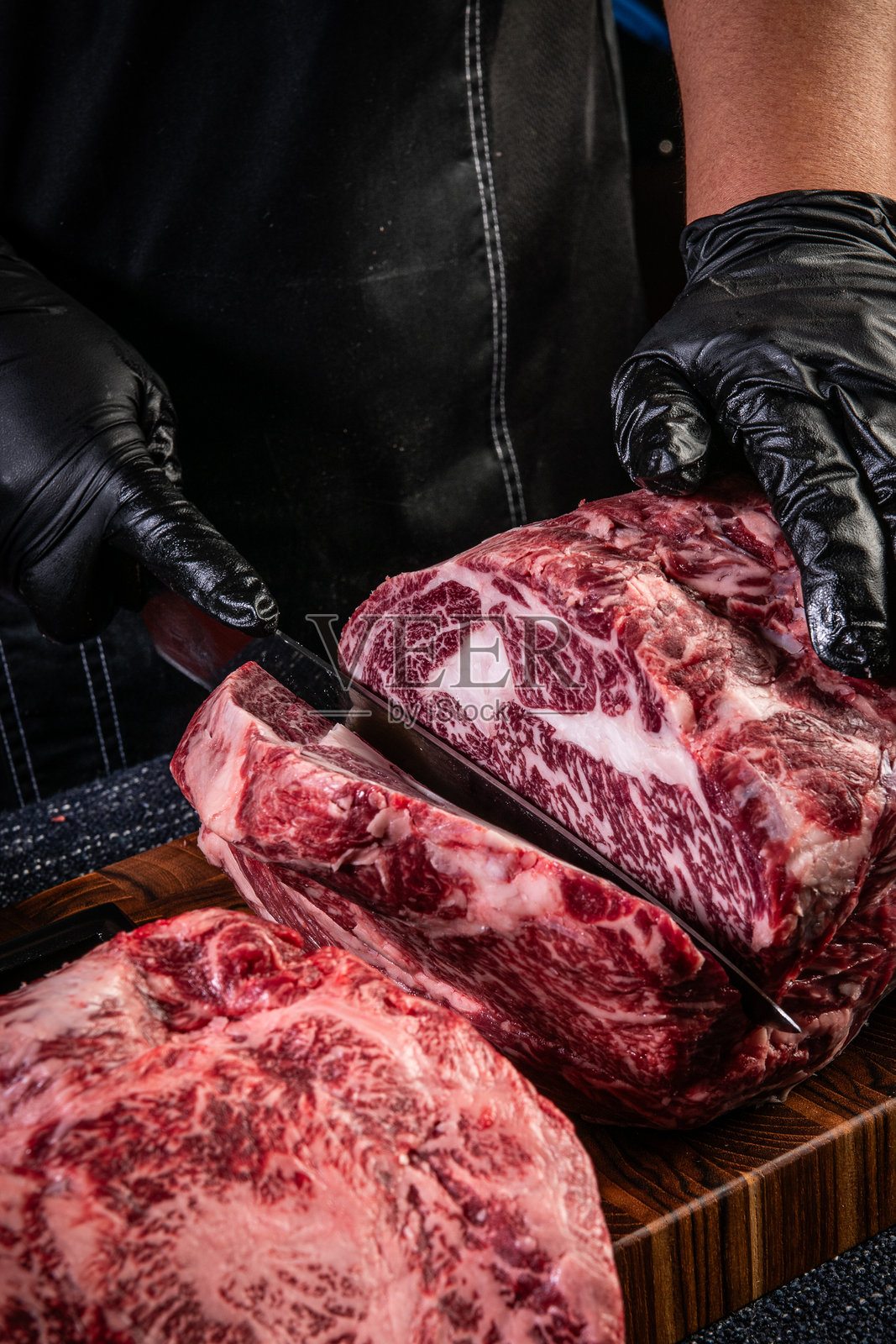 肉贩熟练地切割一块大理石纹生牛排照片摄影图片